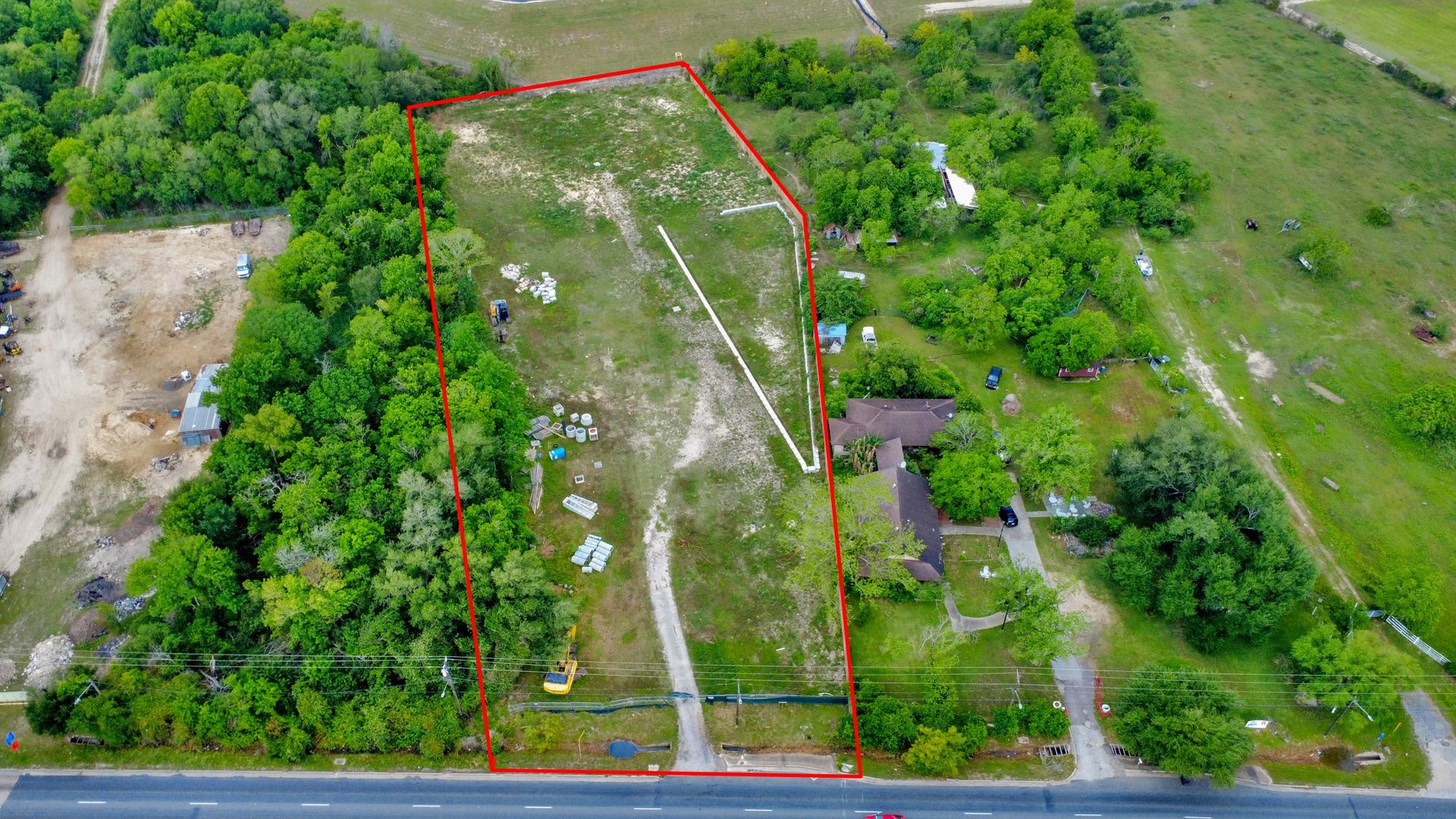 11826 Almeda Road, Houston, TX 77045 This aerial photo showcases a large, rectangular plot of land outlined in red, surrounded by lush greenery. The plot includes a mix of open space and trees, with a few structures visible. It borders a main road, offering easy access. Ideal for development or a private retreat.