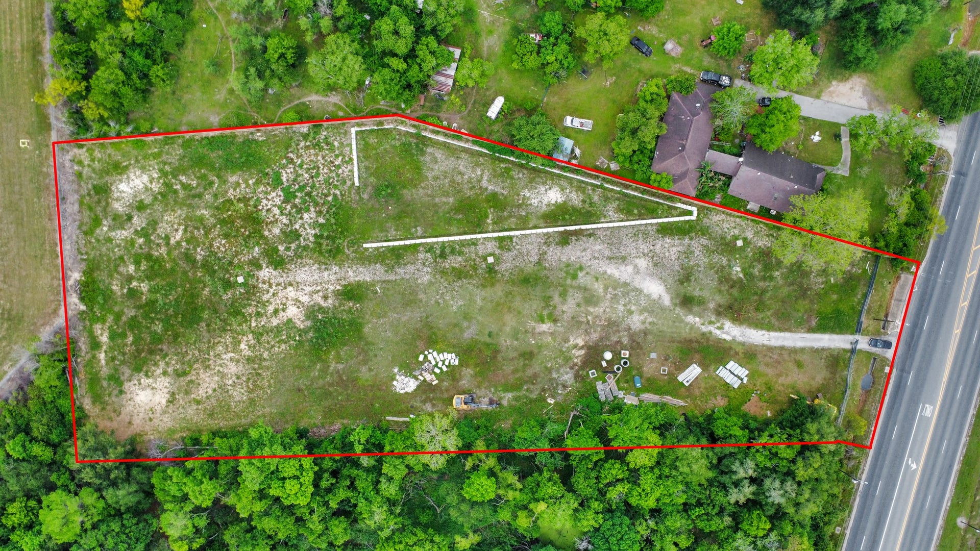 11826 Almeda Road, Houston, TX 77045 This aerial photo showcases a sizable, outlined plot of land adjacent to a main road, surrounded by greenery and near industrial buildings. Ideal for development, it offers easy access to transportation and nearby facilities.