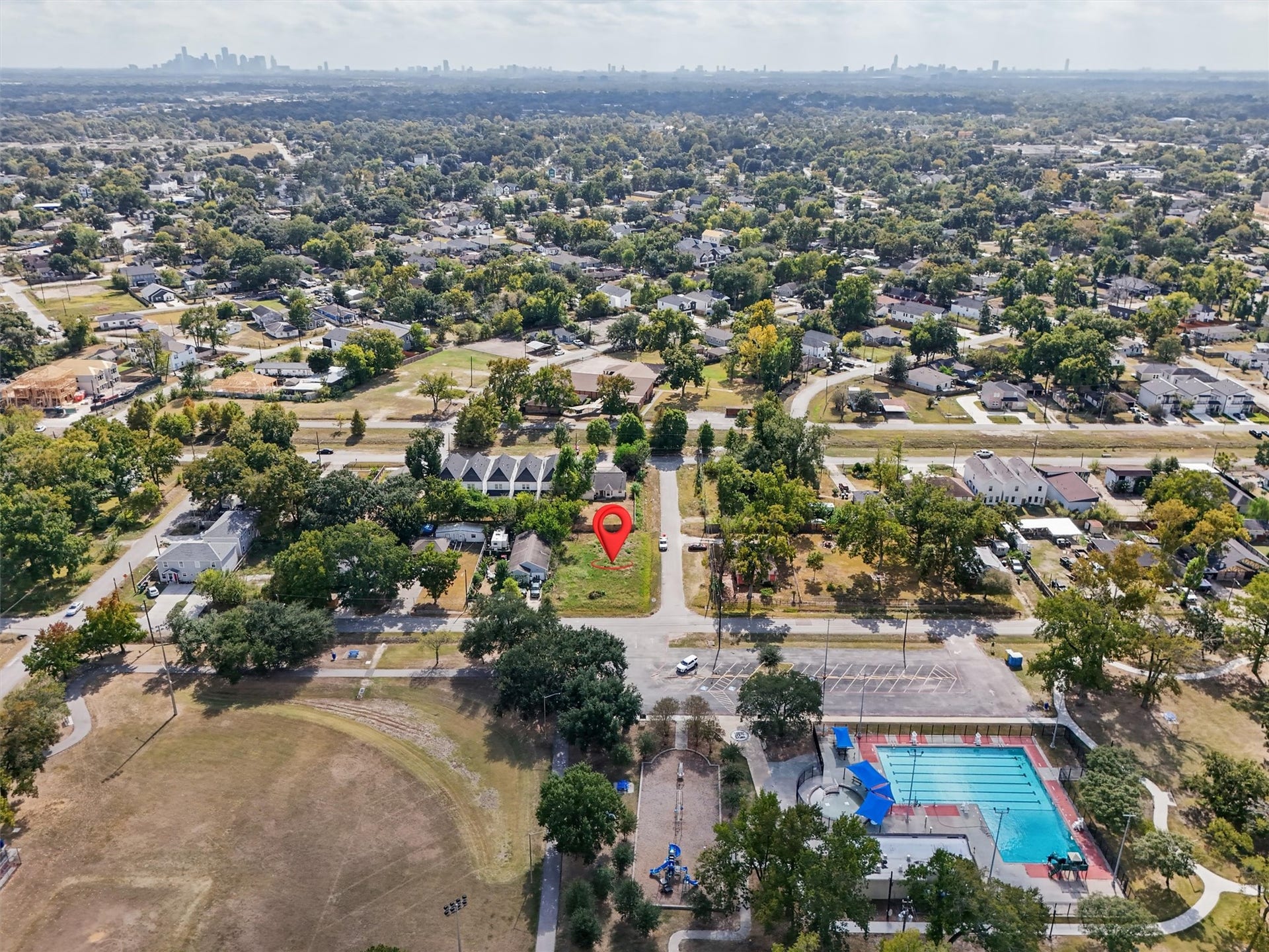 979 Conklin Street, Houston, TX 77088 Location, location, location! This aerial view highlights the cleared corner lot, identified by the red marker, and its surrounding established residential neighborhood. Enjoy close proximity to a community swimming pool, playground, recreational fields, walking paths, and open green spaces. The neighborhood features mature trees, a mix of traditional and newer homes, and convenient access to surrounding streets.