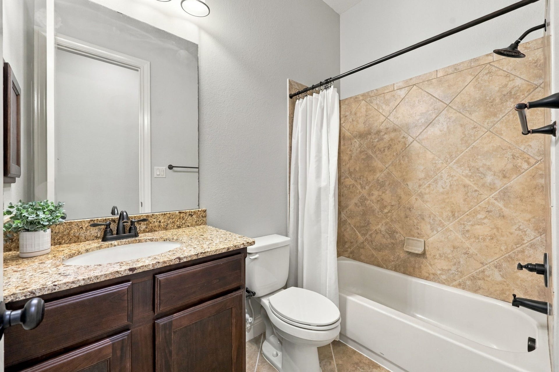27302 Liberty Heights Lane, Fulshear, TX 77441 This Full Bathroom serves Bedroom #4, shown in the previous photo, and features granite countertops, an undermount sink, and beautiful espresso-colored cabinetry. Oil-rubbed bronze fixtures and coordinating lighting add a touch of elegance, while the tub and shower combination includes a built-in soap dish for added convenience.