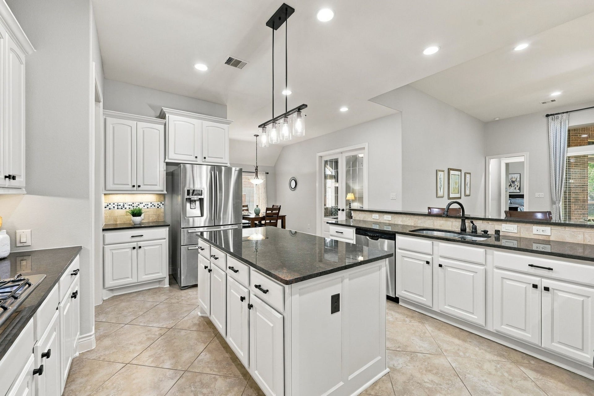 27302 Liberty Heights Lane, Fulshear, TX 77441 The spacious Kitchen is a chef's delight, featuring abundant gorgeous granite countertops, crisp white cabinetry, and a large center island that provides additional workspace and a natural gathering spot. With plenty of room for meal preparation and entertaining, this kitchen combines timeless style with everyday functionality.