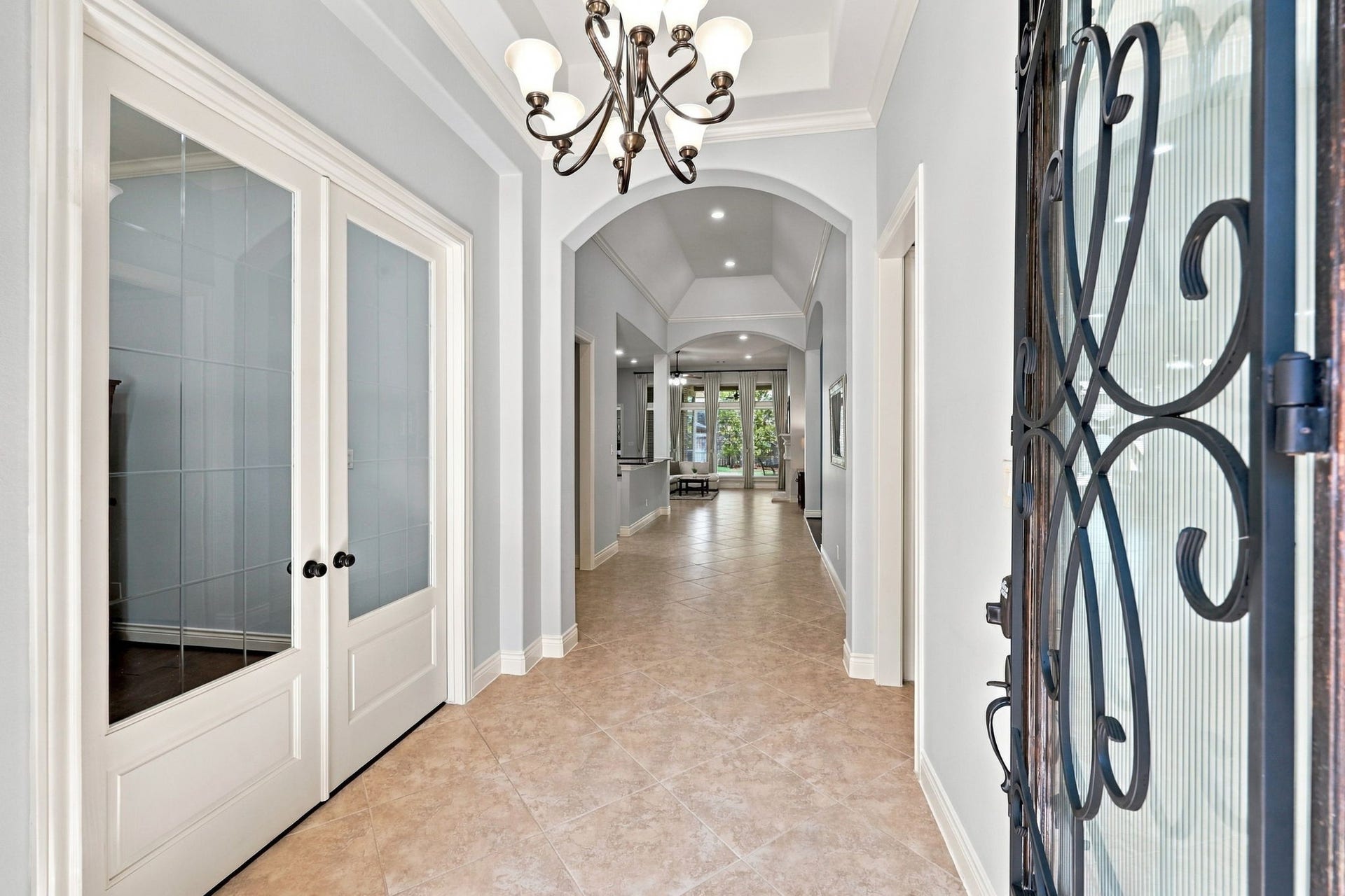 27302 Liberty Heights Lane, Fulshear, TX 77441 As you make your way inside, you are greeted by 18x18 tile flooring laid on a 45-degree angle and an impressive 13-foot ceiling in the foyer, highlighted by a striking eight-globe wrought-iron chandelier. Architectural arches add character and elegance, while double glass doors to the left open to the home office. The welcoming entryway offers an extended sightline through the home, creating an immediate sense of space and openness.
