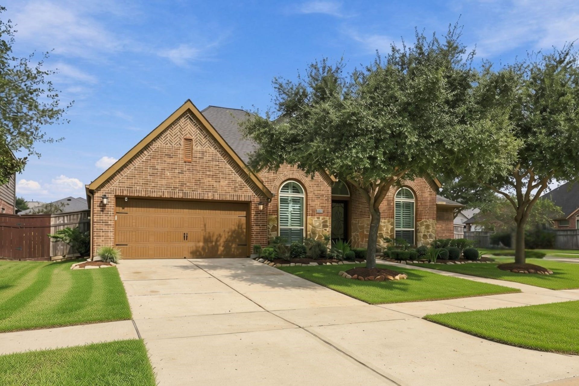27302 Liberty Heights Lane, Fulshear, TX 77441 Situated on an oversized corner lot with no neighbors to the right, this beautiful one-story home offers added privacy and attractive curb appeal with a combination of brick and stone exterior. The double-wide driveway provides ample parking and leads to a spacious three-car tandem garage, accented by coach lights on either side.