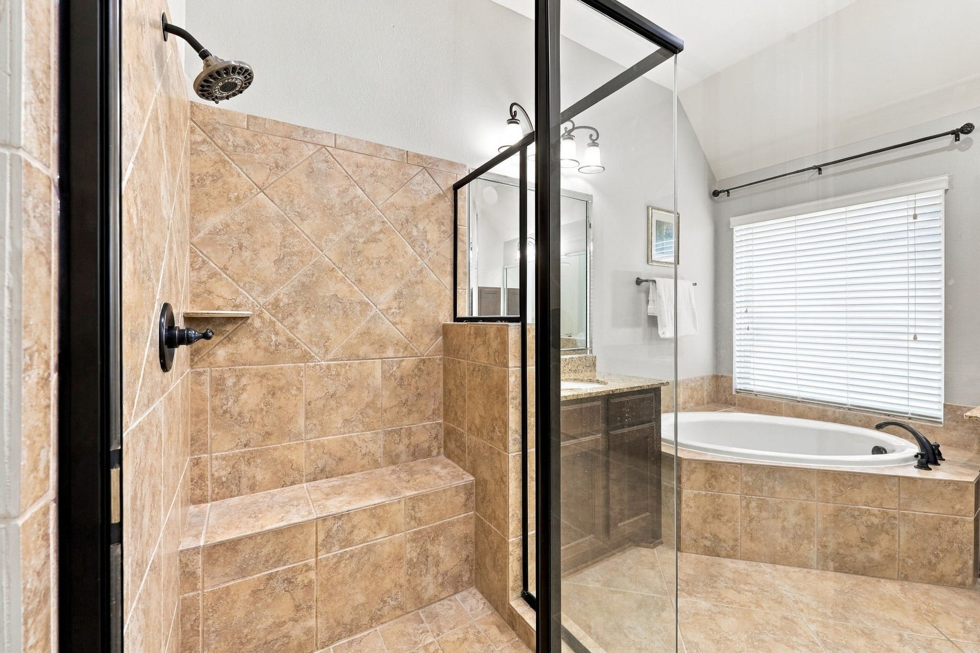 27302 Liberty Heights Lane, Fulshear, TX 77441 The spacious walk-in shower features a framed glass enclosure, a built-in bench, and a convenient recessed soap dish, combining comfort and functionality in the Primary Bathroom.