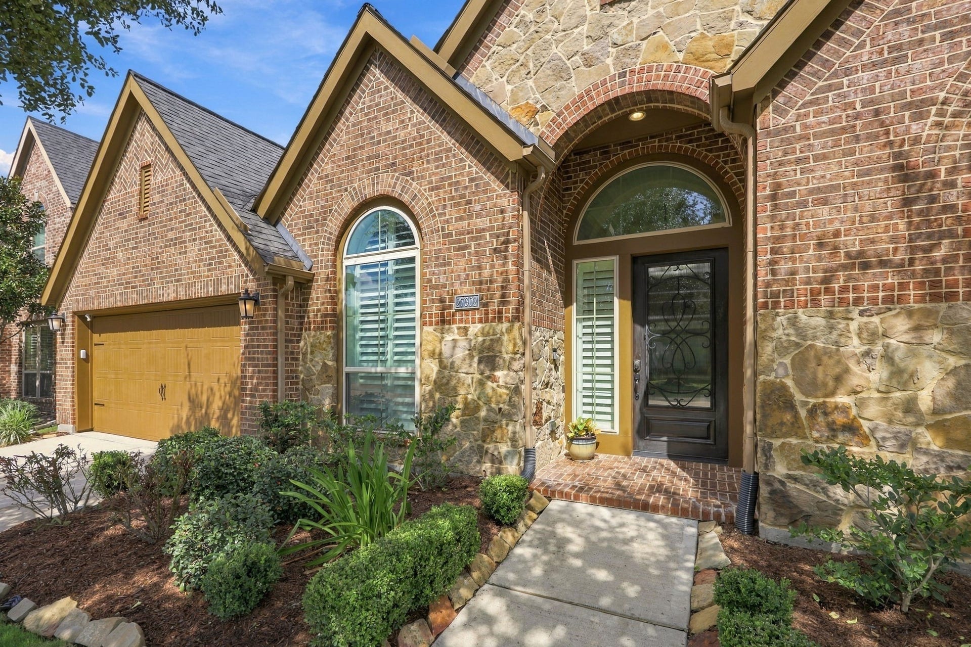 27302 Liberty Heights Lane, Fulshear, TX 77441 As you make your way to the front entrance, you'll notice the beautifully landscaped beds bordered with stone, adding a polished touch to the home's exterior. The inviting arched, covered front porch features charming brick accents and brick flooring, creating a warm and welcoming entry.