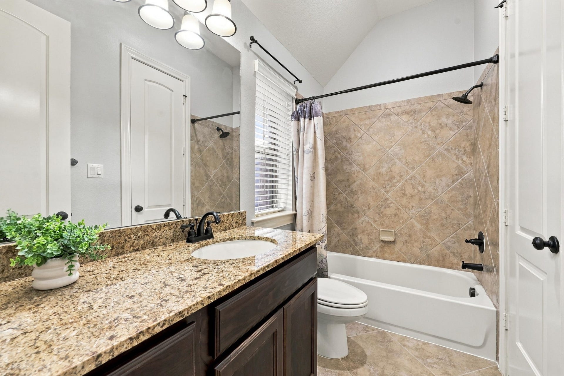 27302 Liberty Heights Lane, Fulshear, TX 77441 The adjoining Bathroom serves the Bedroom shown in the previous photo and features a spacious vanity with an undermount sink, rich espresso cabinetry, and coordinating oil-rubbed bronze faucets and light fixtures. A tub and shower combination offers added convenience and functionality.