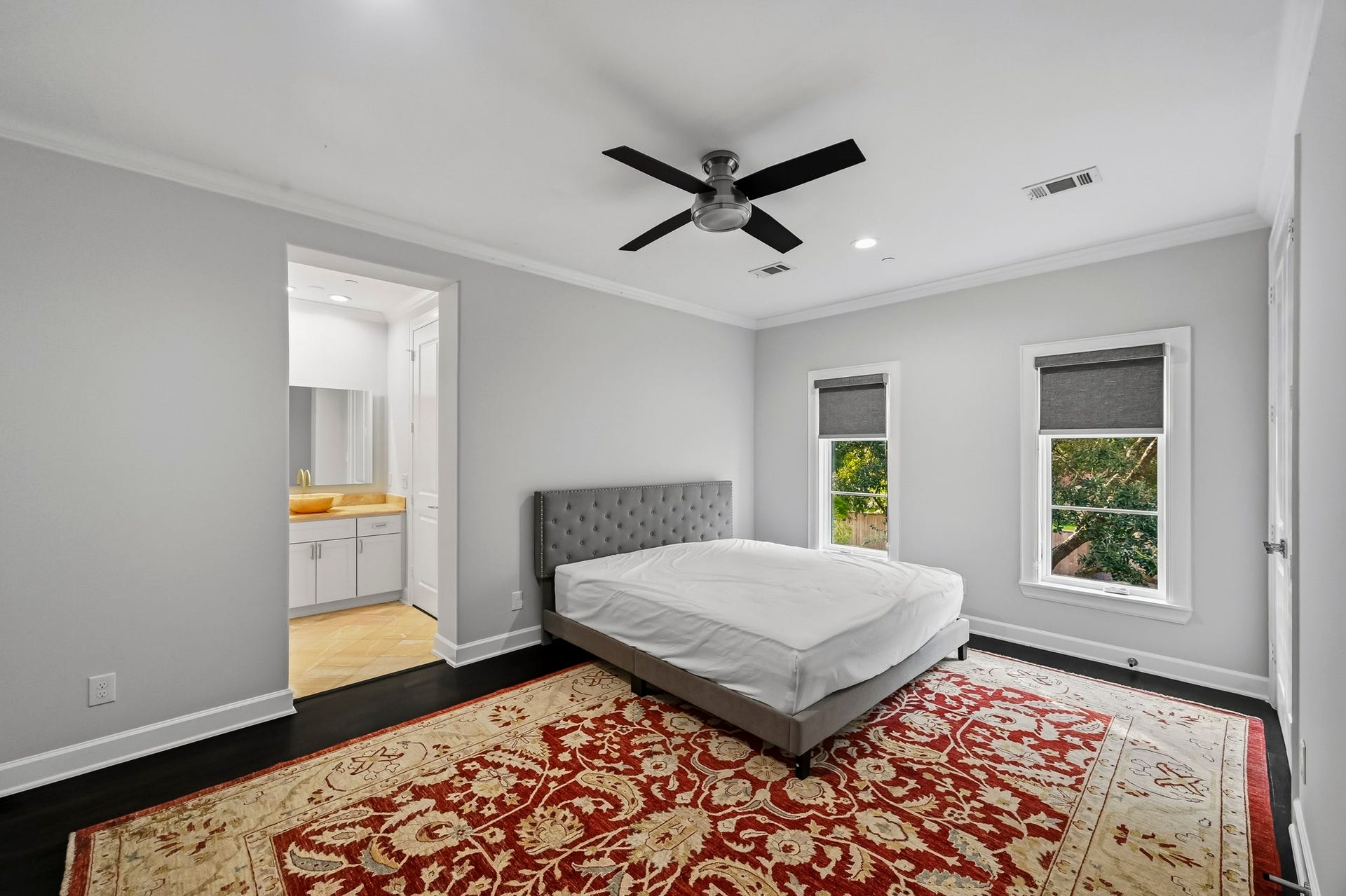 Spacious bedroom with a tall ceilings, a ceiling fan, and large windows providing ample natural light. The room features an en suite bathroom.