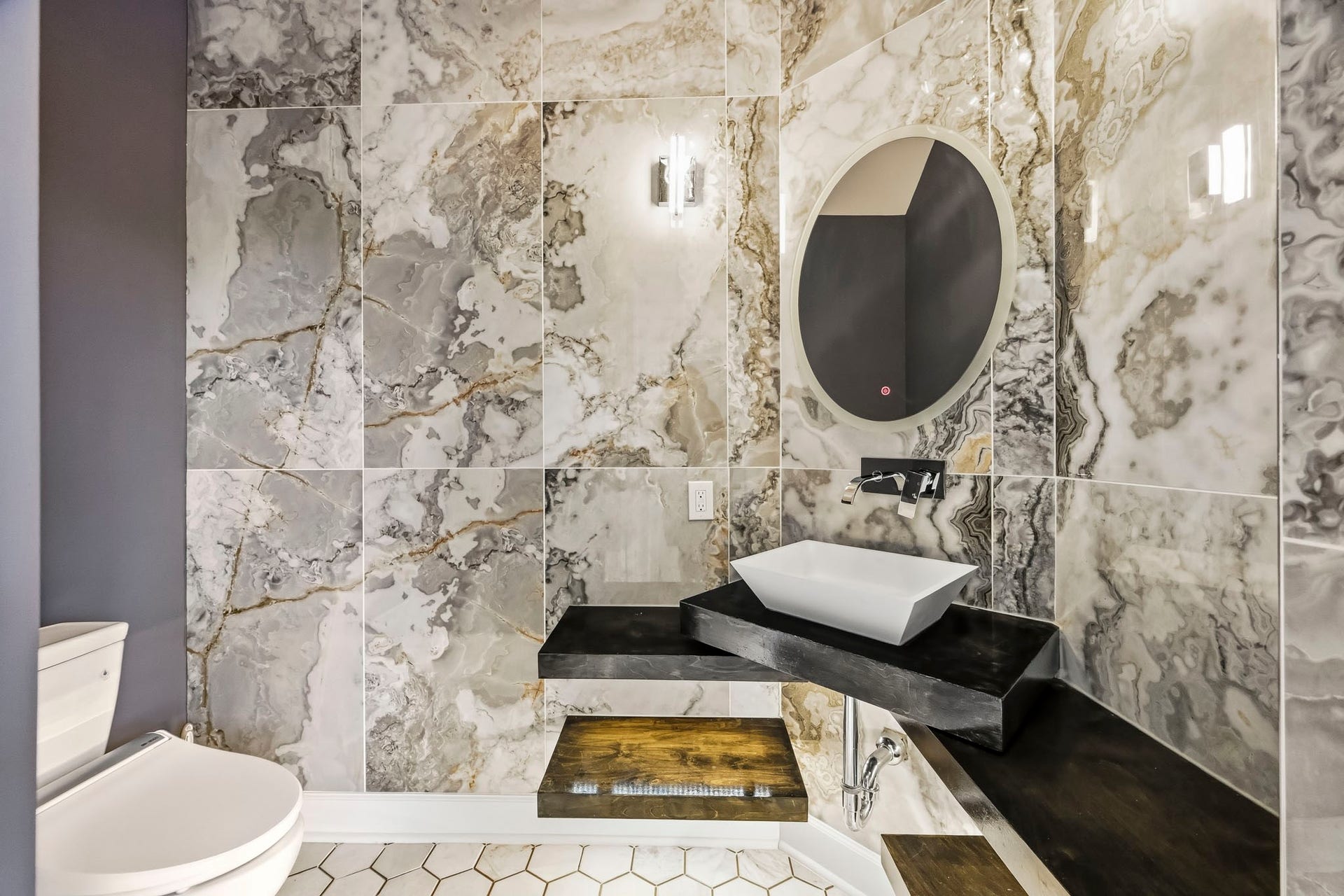 Luxurious half bathroom featuring stunning marble walls, a modern vessel sink, and sleek black fixtures, creating a sophisticated and elegant space.