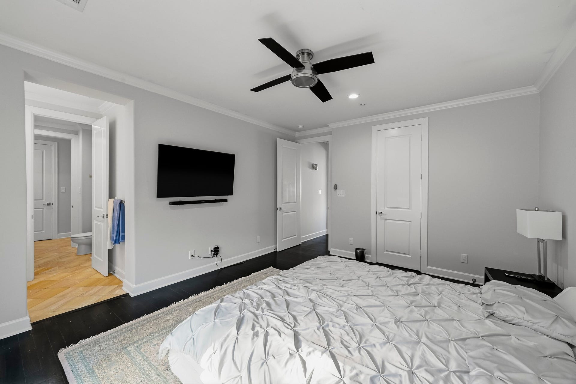 Spacious secondary bedroom featuring sleek dark flooring, and a modern ceiling fan.