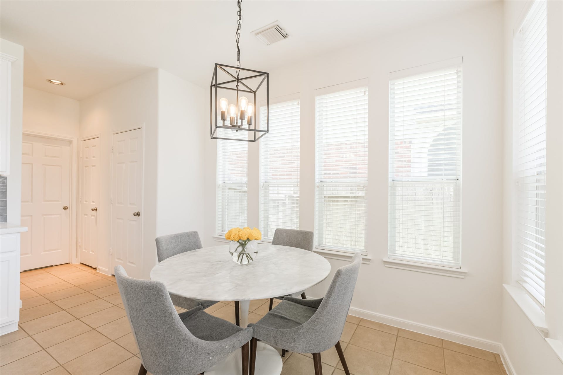 10314 Five Oaks Crossing, Missouri City, TX 77459 Bright dining area with large windows, neutral tile flooring, and a modern chandelier.