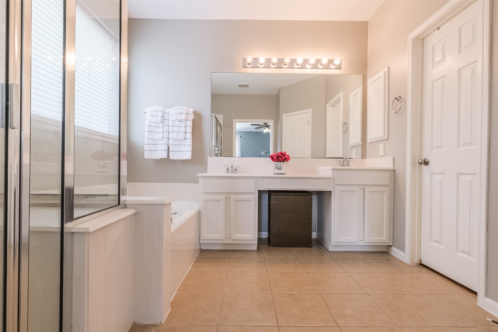10314 Five Oaks Crossing, Missouri City, TX 77459 This bathroom features a spacious layout with a large mirror and dual sinks on a white vanity. It includes a separate shower, a soaking tub, and ample lighting, creating a bright and inviting space.