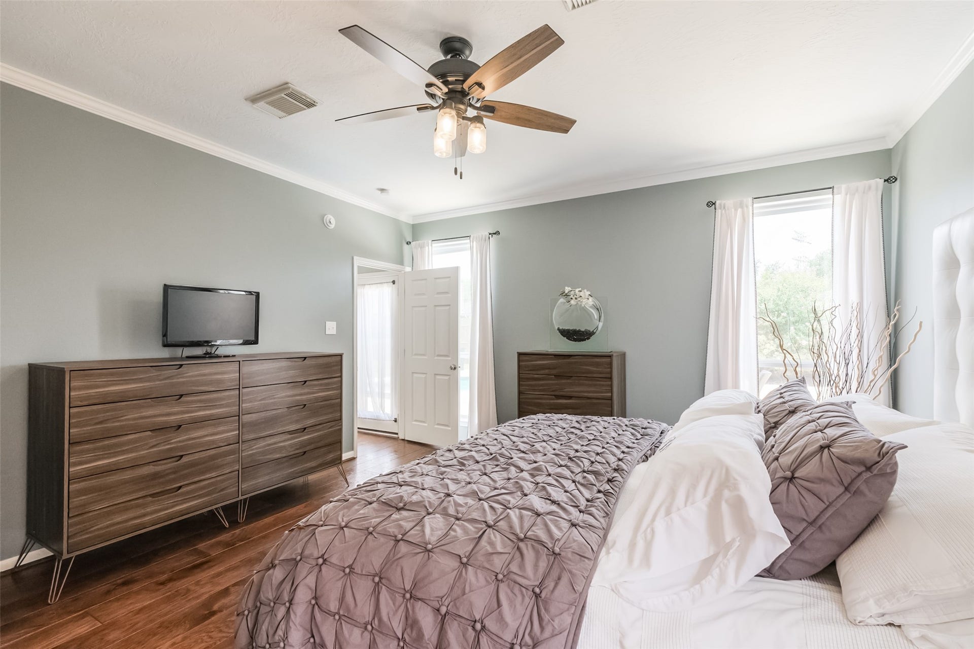 10314 Five Oaks Crossing, Missouri City, TX 77459 This primary bedroom features hardwood floors, a ceiling fan, and soft gray walls.