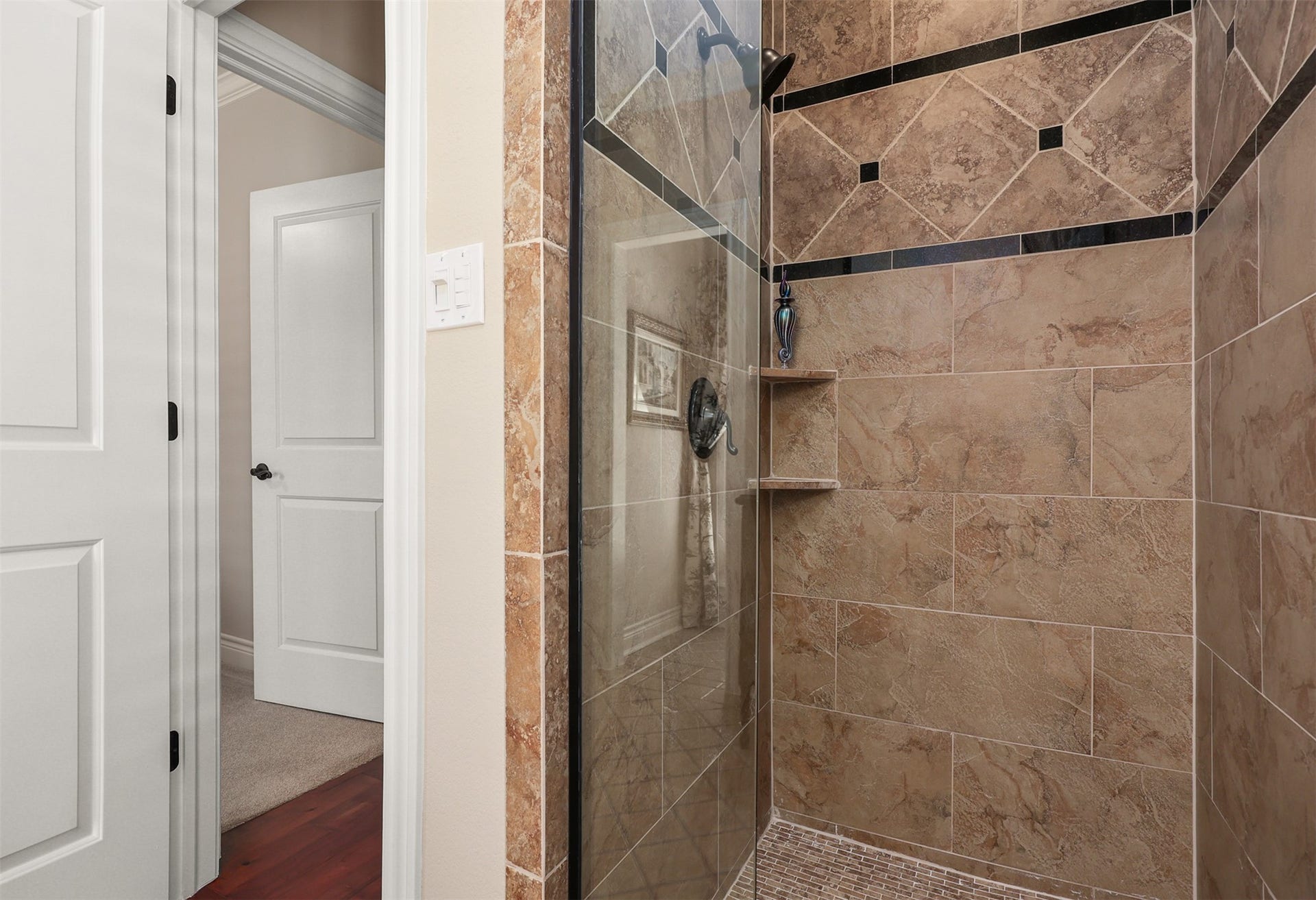 18607 Point Lookout Drive, Nassau Bay, TX 77058 The adjoining bath to bedroom #1 features a spacious walk-in shower with beautiful custom tilework and a sleek, frameless glass shower door.