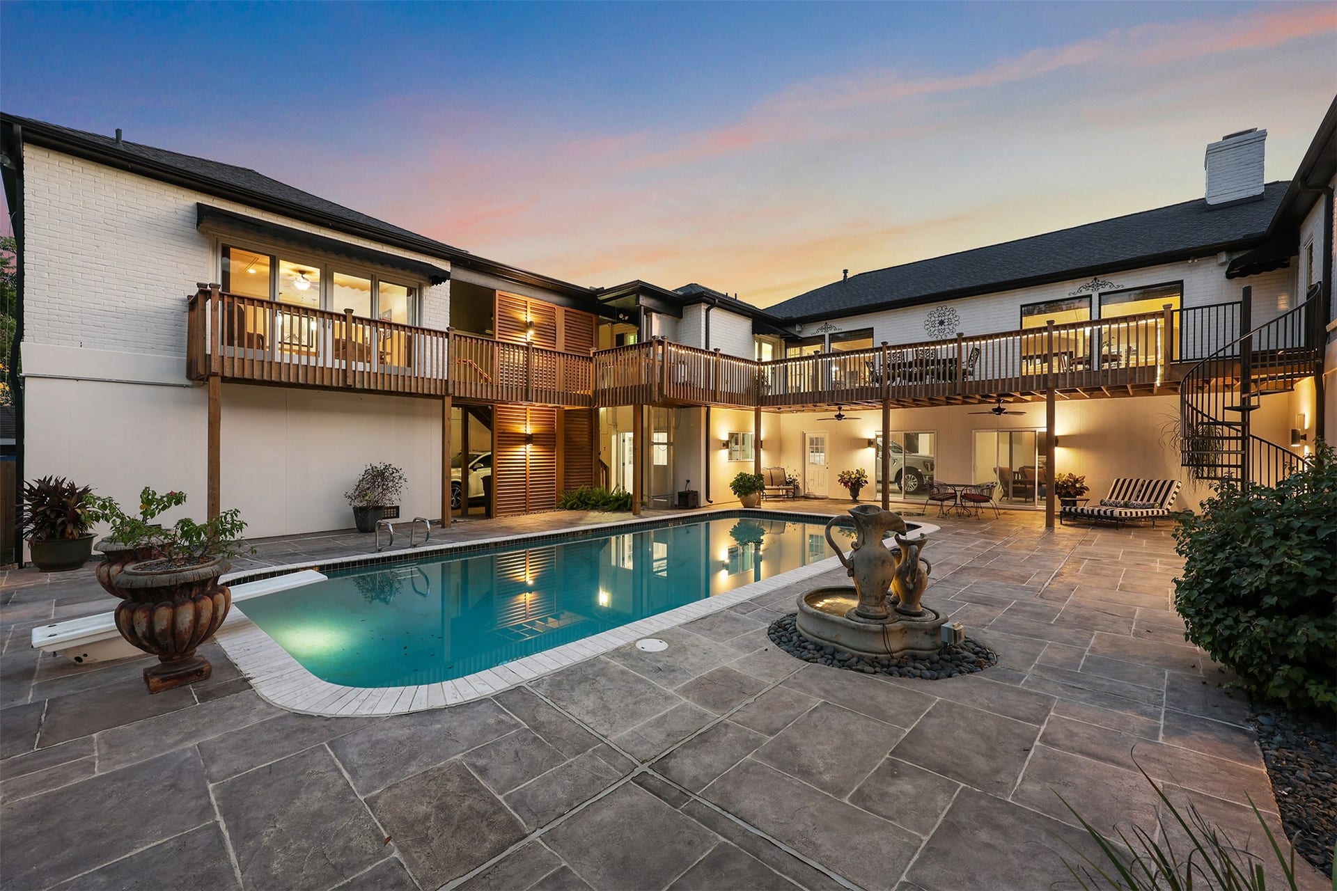 18607 Point Lookout Drive, Nassau Bay, TX 77058 A stunning evening view captures the beauty of this exceptional outdoor retreat! Warm architectural lighting highlights the stained wood louvers, while four expansive picture windows overlook the sparkling pool from the home's main living area. The charming spiral staircase, elevated decks, and inviting pool house create a spectacular setting for entertaining or relaxing uncer the stars.