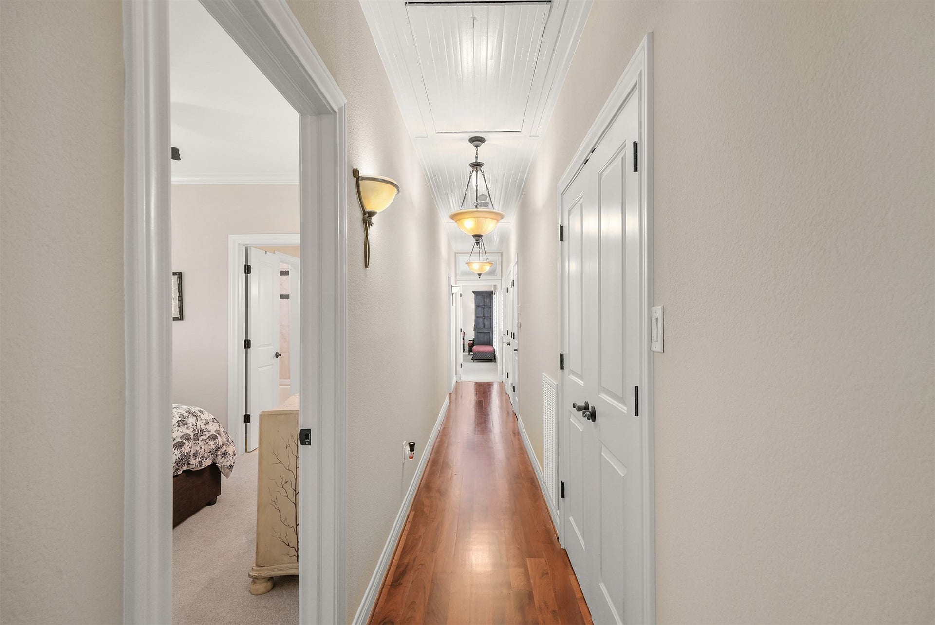 18607 Point Lookout Drive, Nassau Bay, TX 77058 This beautiful hallway features solid mesquite wood flooring, decorative beadboard ceiling detailing, elegant lighting, and abundant storage, including a walk-in cedar closet. Bedroom #2, located to the left, has access to a full bath that can also serve the adjoining room, currently used as an office. Another example of the thoughtful custom details found throughout this home.