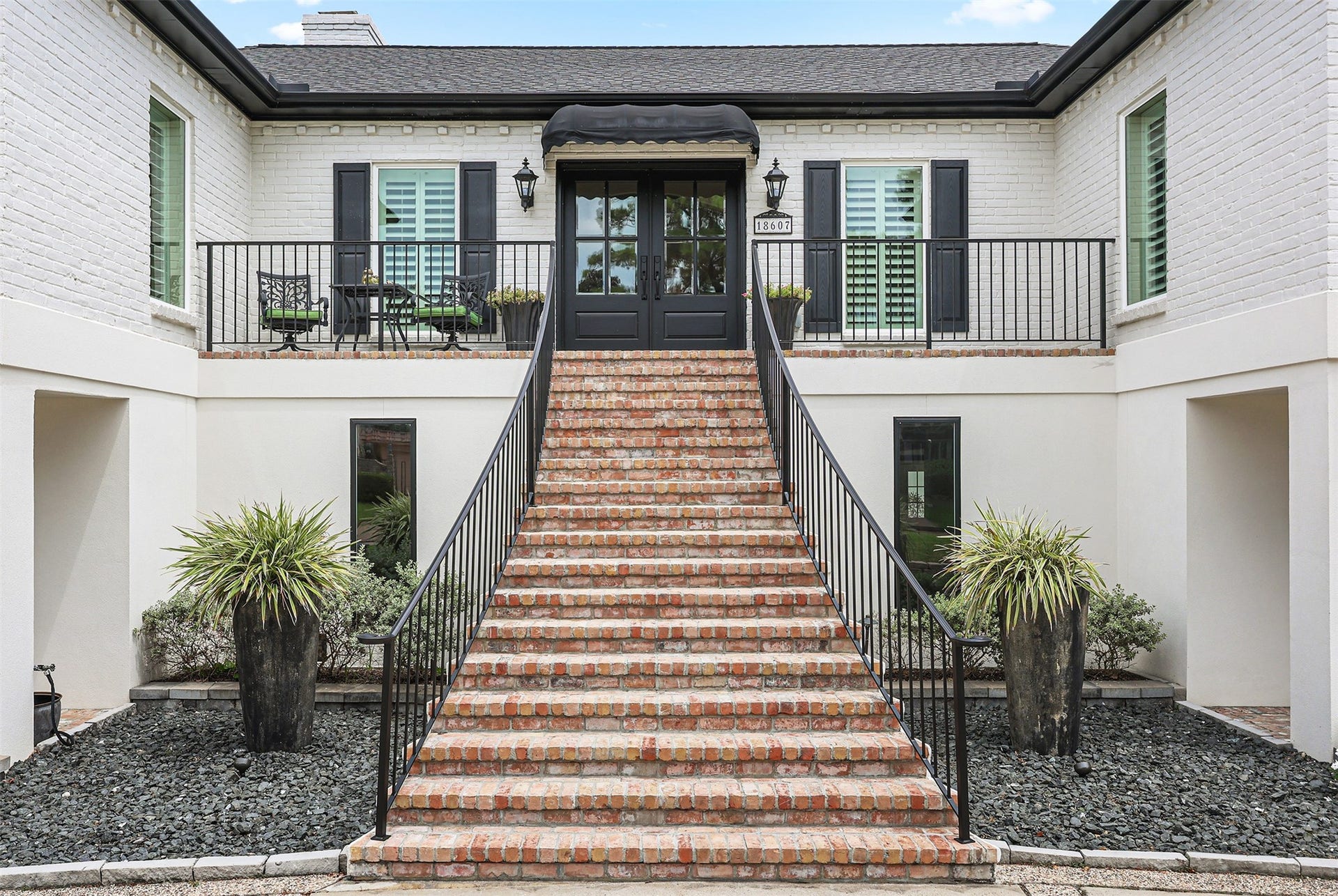 18607 Point Lookout Drive, Nassau Bay, TX 77058 A grand brick staircase with classic wrought-iron railings welcomes you to this beautifully designed home. Elegant black double entry doors, charming lantern lighting, plantation shutters, and an inviting front porch create a timeless entrance filled with character and Southern charm.