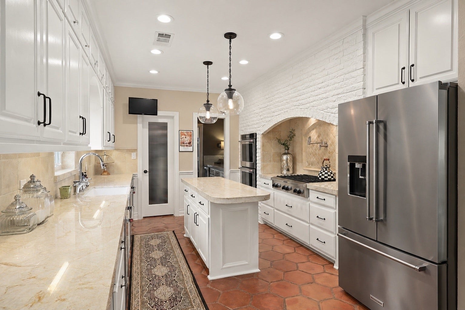 18607 Point Lookout Drive, Nassau Bay, TX 77058 View from the breakfast area looking toward the wet bar, with a spacious walk-in pantry and convenient ice maker to the left. Two beautiful glass pendant lights add elegance, while the television mounted above the pantry conveys with the house.