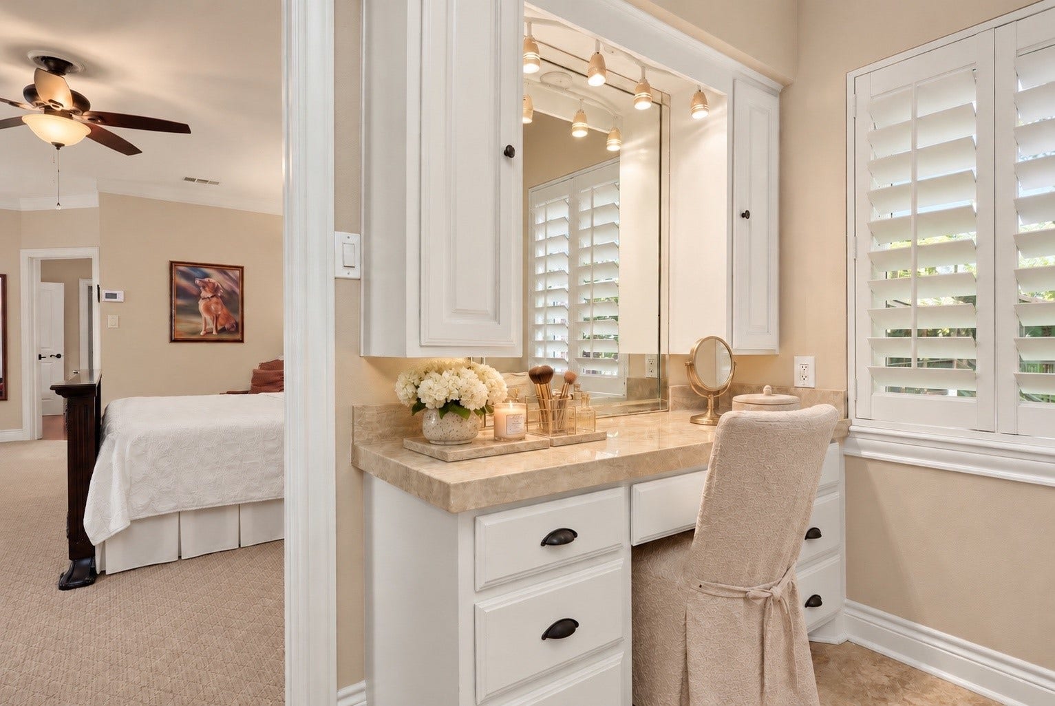 18607 Point Lookout Drive, Nassau Bay, TX 77058 Charming makeup vanity features an elegant Taj Mahal countertop and a nearby window providing beautiful natural light. The primary bath also offers separate his-and-hers walk-in closets, and a spacious linen closet with a convenient built in laundry hamper, providing exceptional storage and organization.