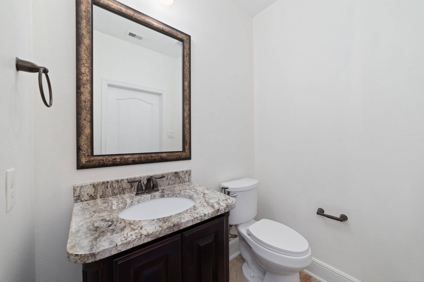 11103 Dowbeck Avenue, Richmond, TX 77407 This half bathroom features a sleek design with a granite countertop, and dark wood vanity.