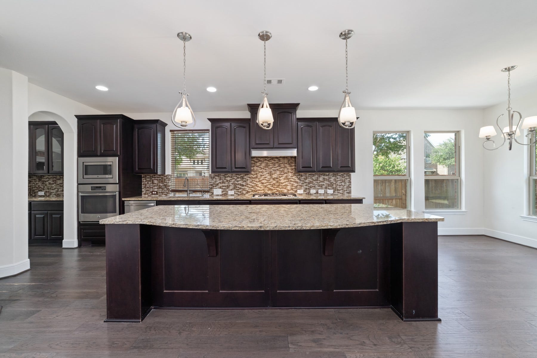 11103 Dowbeck Avenue, Richmond, TX 77407 This modern kitchen features elegant dark wood cabinetry, a large center island, and stainless steel appliances.