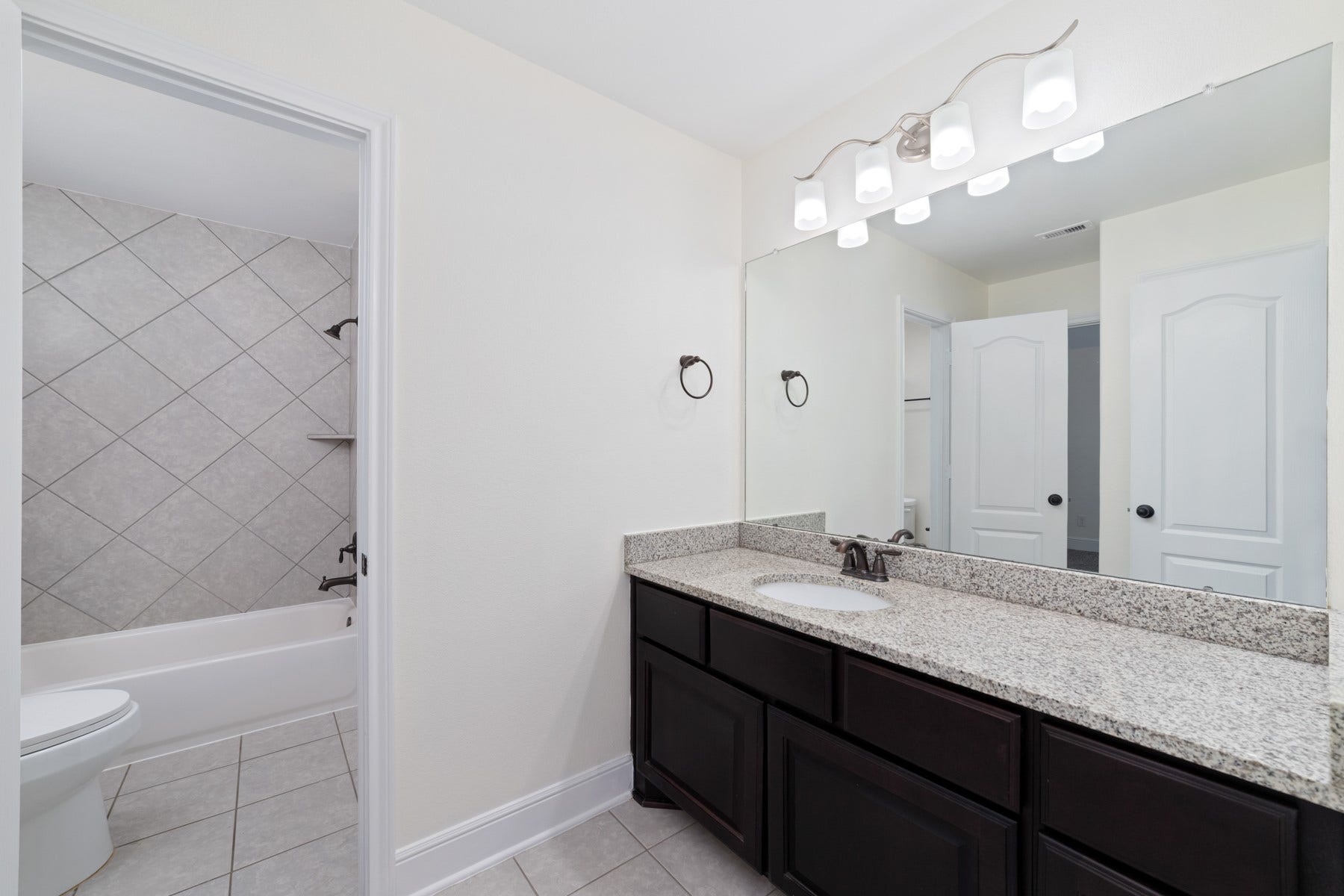 11103 Dowbeck Avenue, Richmond, TX 77407 This bathroom features a modern design with dual sinks, and sleek dark cabinetry.