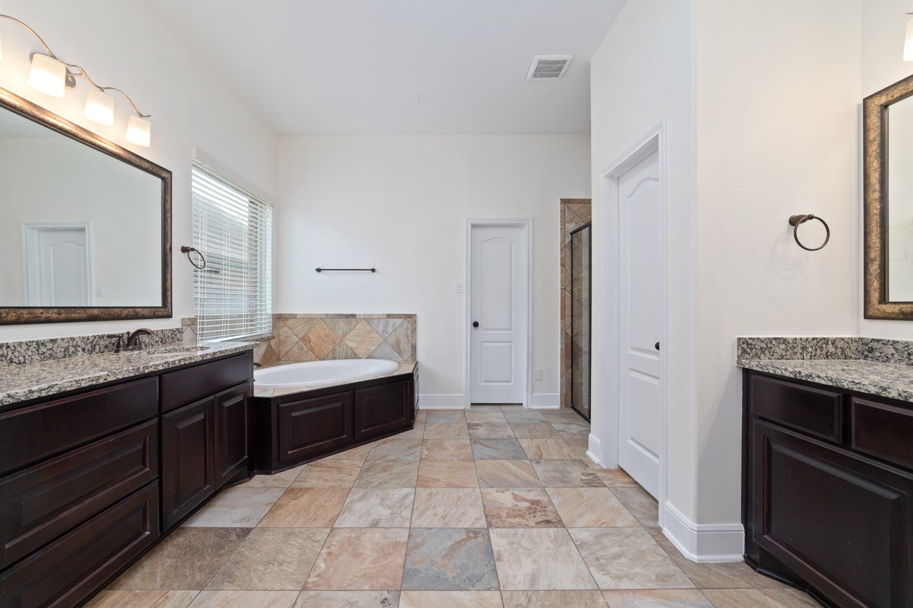 11103 Dowbeck Avenue, Richmond, TX 77407 Featuring a luxurious soaking tub, elegant dark wood cabinetry, and a large window for natural light.