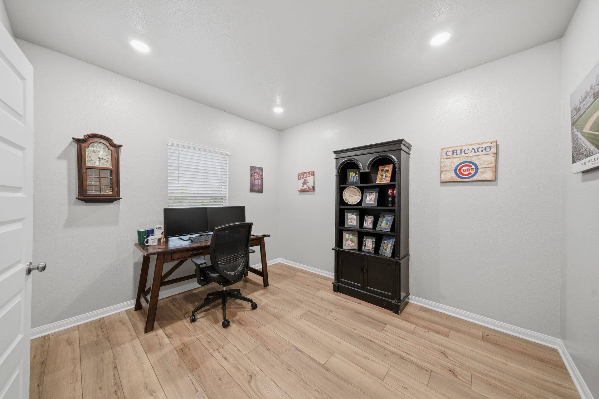 Bright and inviting home office featuring modern recessed lighting, warm vinyl plank wood-look floors, and a stylish workspace.