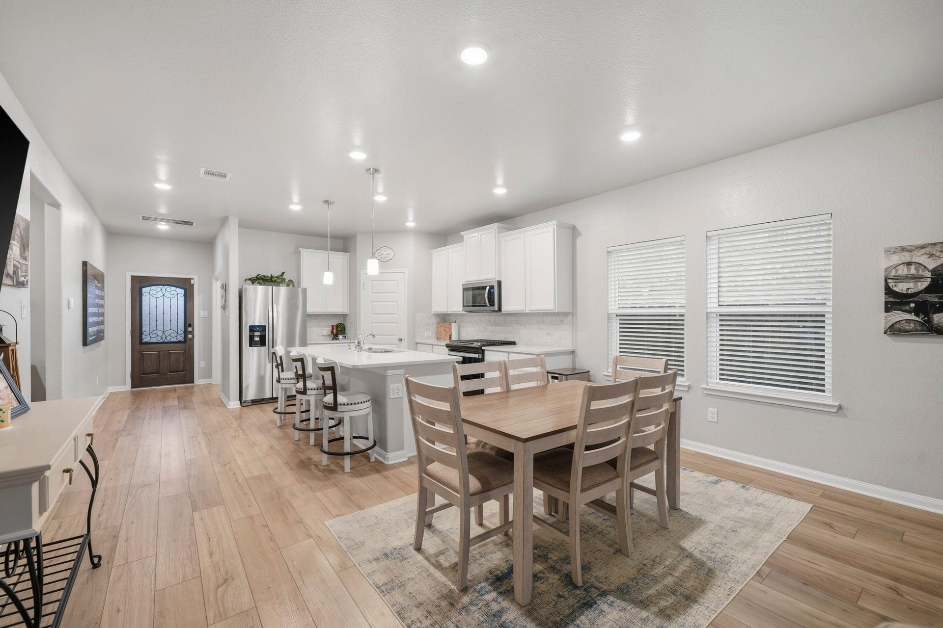 Spacious and bright kitchen and dining area featuring modern appliances, a large island with seating, and popular vinyl plank flooring perfect for entertaining.