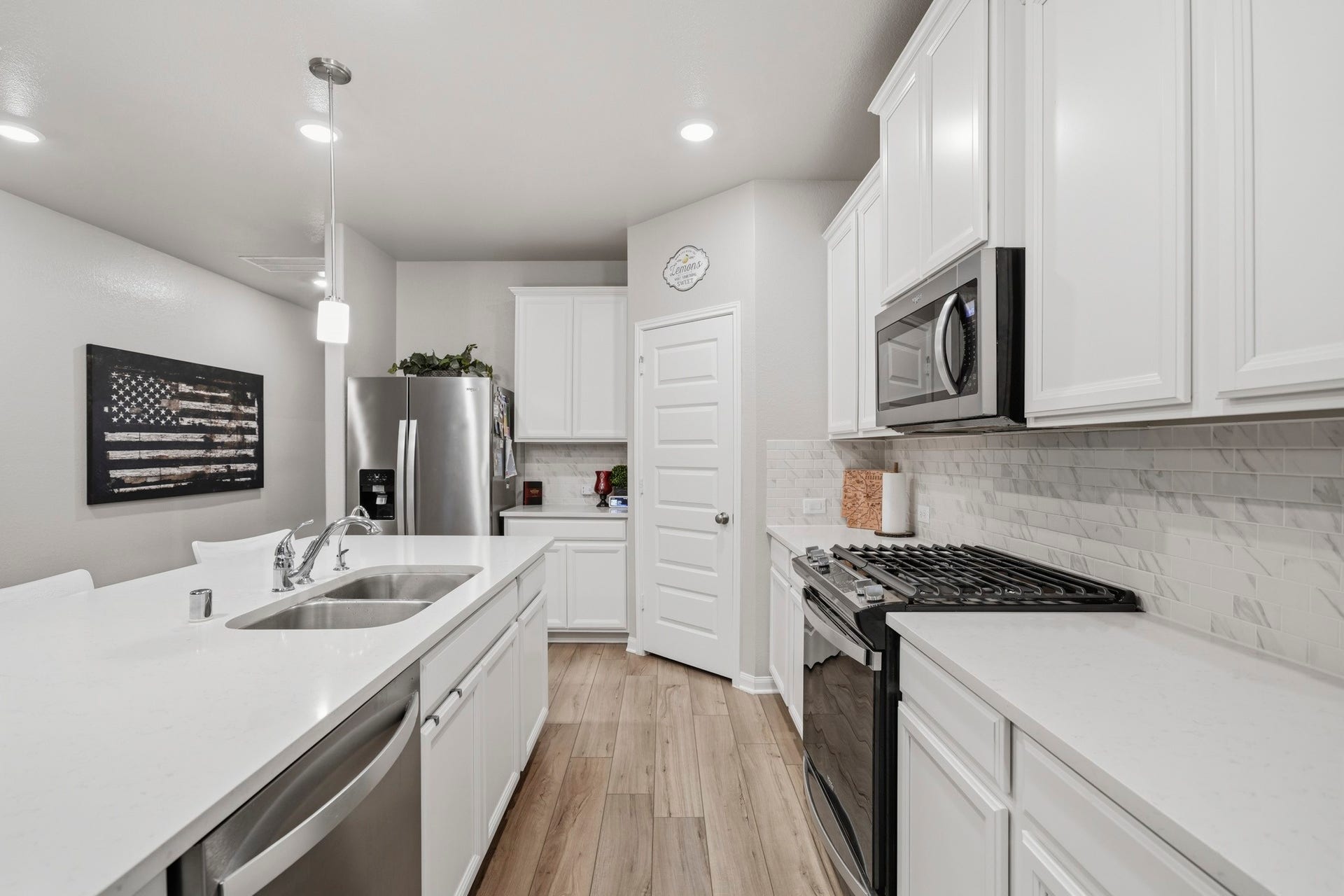 Modern kitchen with sleek white cabinetry, stainless steel appliances, and a spacious island with dual sinks.