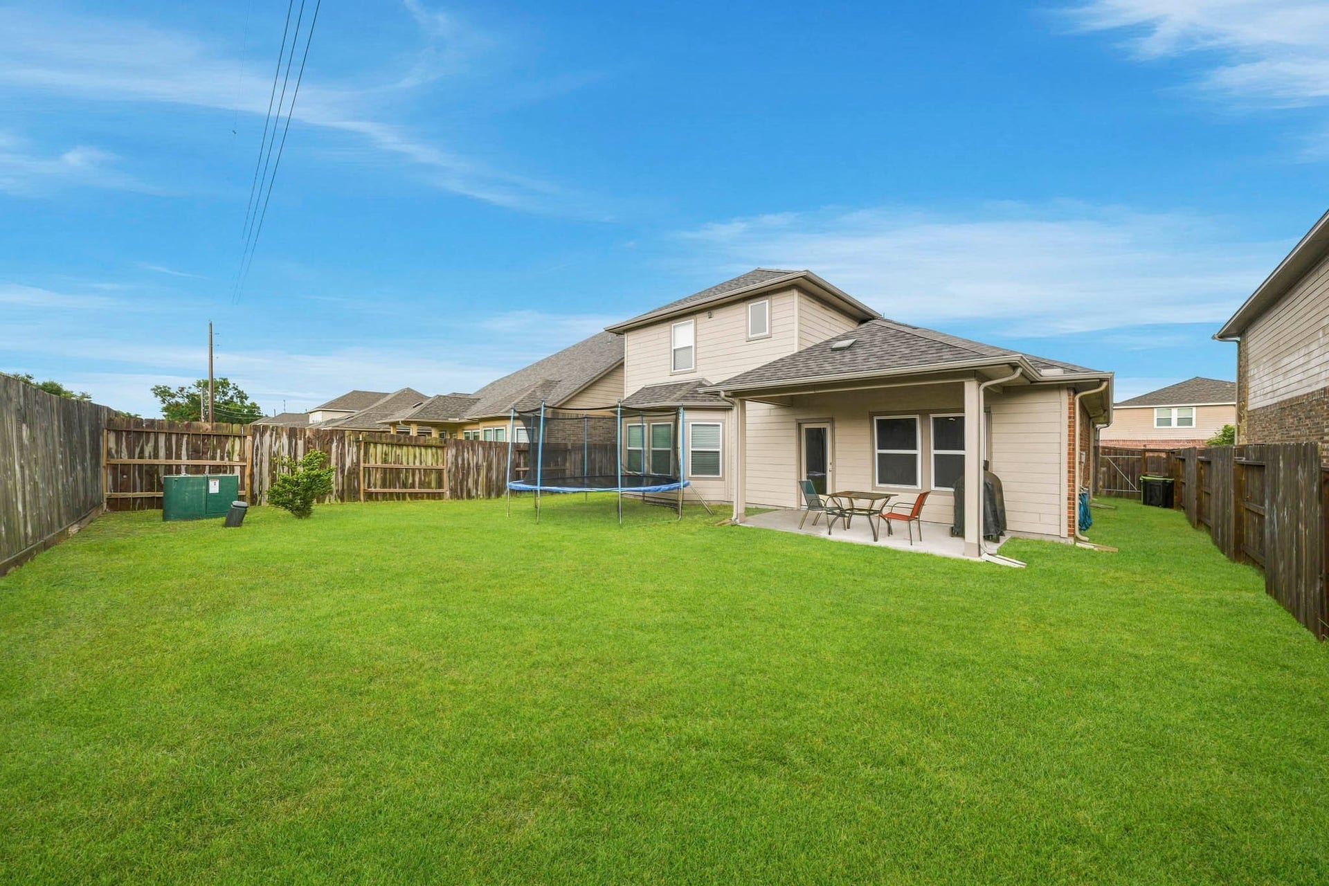 Spacious fenced backyard with a covered patio, perfect for outdoor gatherings and relaxation.