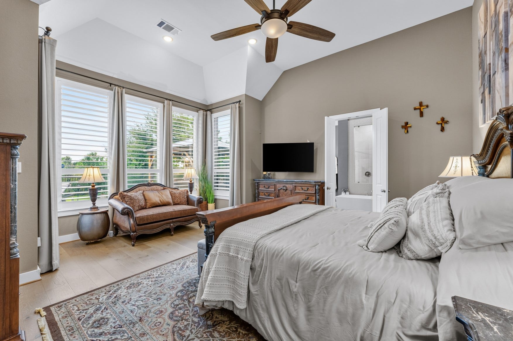 2214 Almond Creek Lane, Fulshear, TX 77423 Sunlight pours into your spacious primary suite that features a high ceiling, sitting area surrounded by five tall windows, and warm wood flooring.
