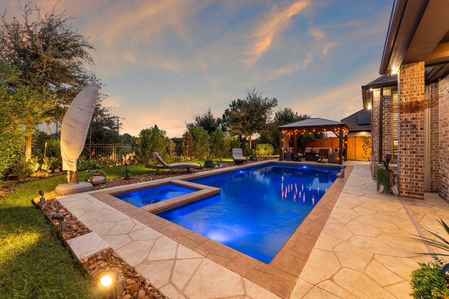 2214 Almond Creek Lane, Fulshear, TX 77423 This backyard is very private with a natural green space behind the fence and a community lake beyond that. Lawn space surrounds the pool. The pool decking pattern resembles natural stone.