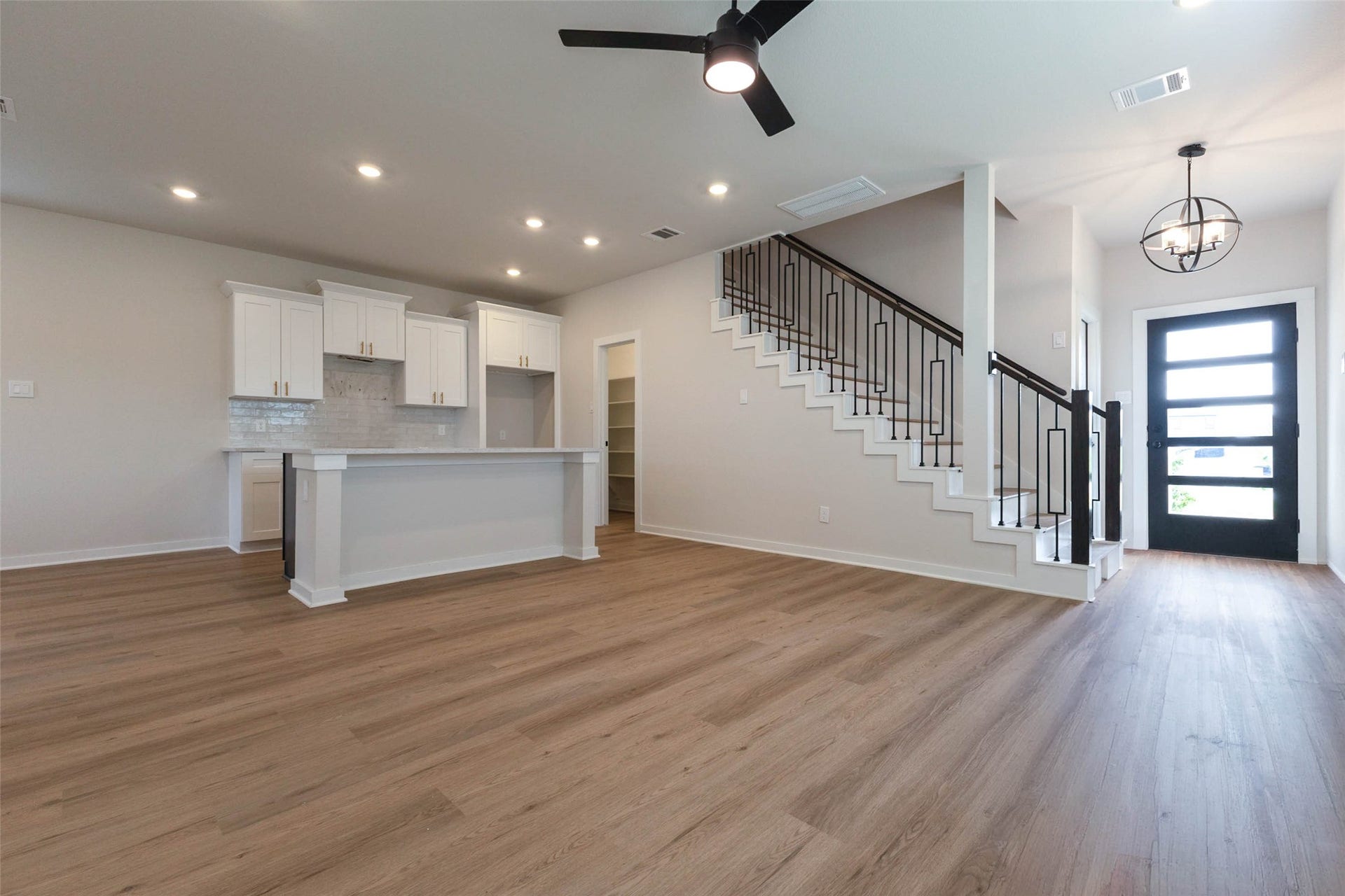 1007 Santee Ct Court, Rosharon, TX 77583 Step through the modern glass-paneled front door into a bright foyer with a globe pendant light and a clear view straight through the open floor plan. The iron-spindle staircase makes a bold design statement, and the wood-look floors lead you toward the kitchen and living space. Recessed lighting and a ceiling fan keep the first impression airy, welcoming and ready for entertaining from day one.