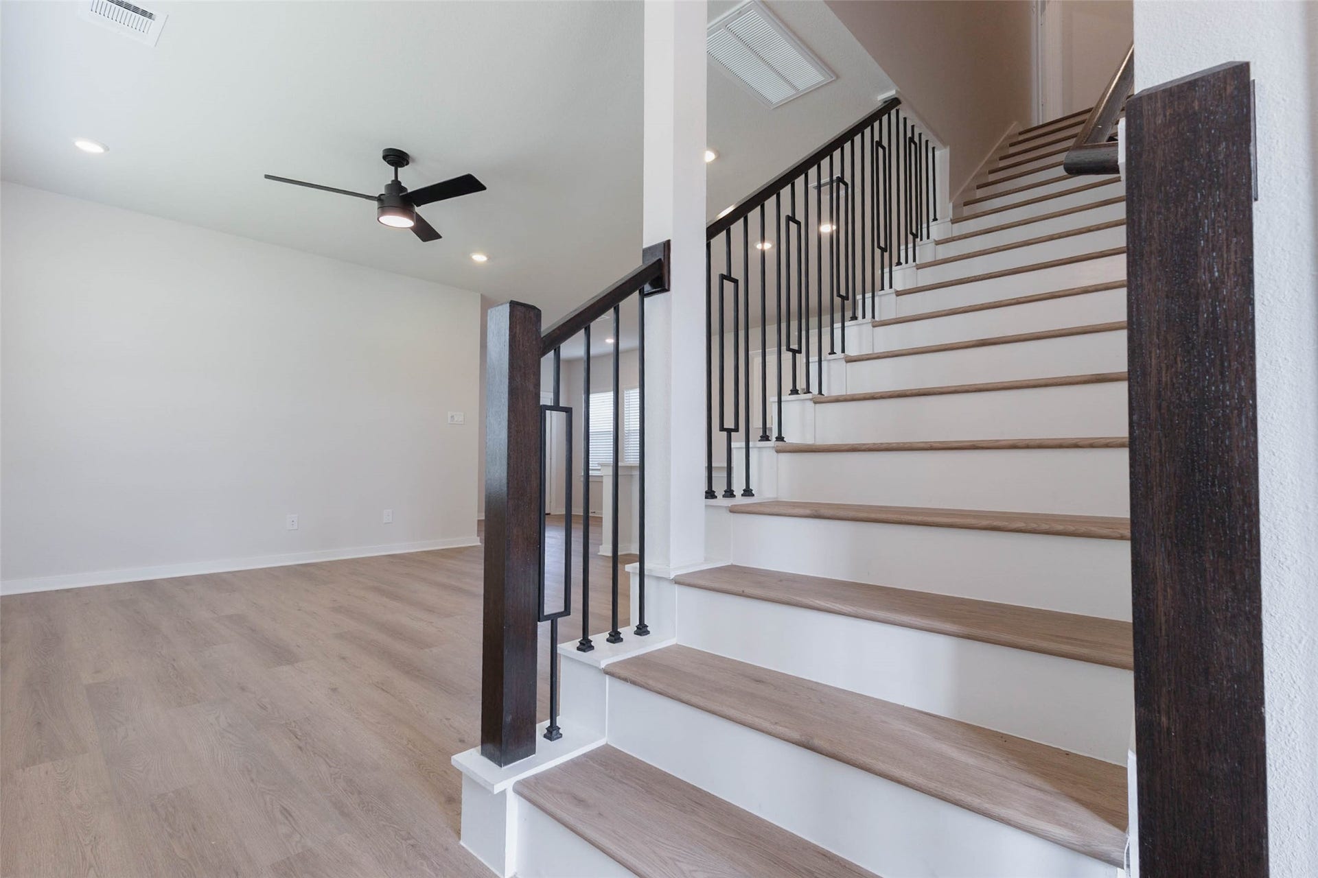 1007 Santee Ct Court, Rosharon, TX 77583 Wood-treaded stairs with black iron spindles and a rich dark newel post make the staircase a design feature as well as the path to the second floor. Natural light spills across the steps from above, and a ceiling fan keeps the landing comfortable. The open stair keeps the main floor feeling connected to the upper level and adds a custom-built look you rarely see at this price.
