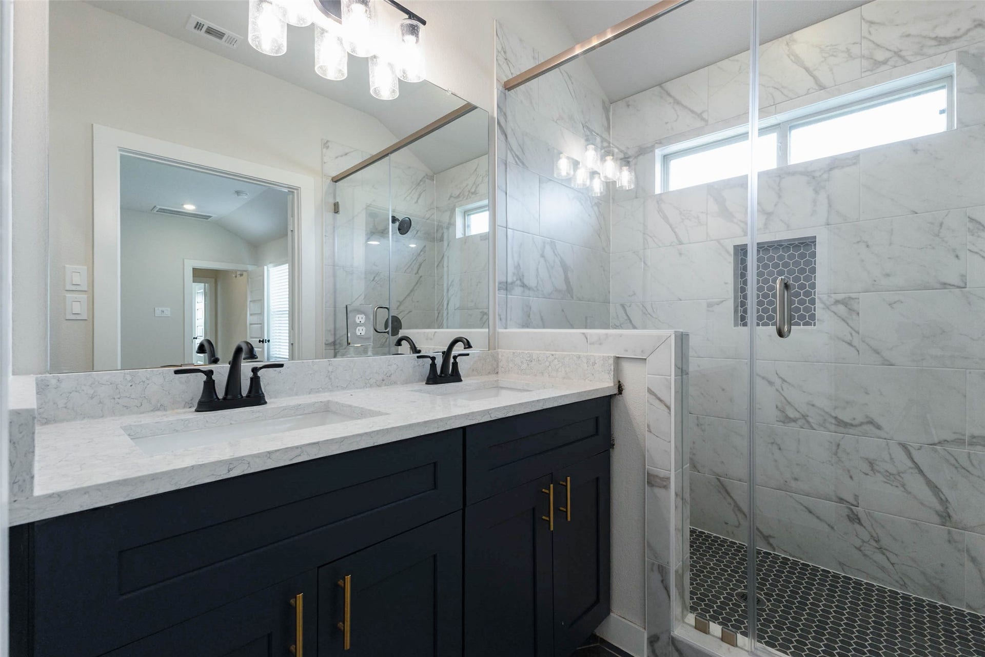 1007 Santee Ct Court, Rosharon, TX 77583 Another view of the primary bath shows the glass-enclosed shower with a built-in niche, hex-tile floor and a high window that brings in daylight while keeping things private. Black faucets contrast beautifully with the white quartz counters and navy vanity cabinets, and the large mirror makes the room feel even bigger. It is a polished, low-maintenance space designed for daily use.