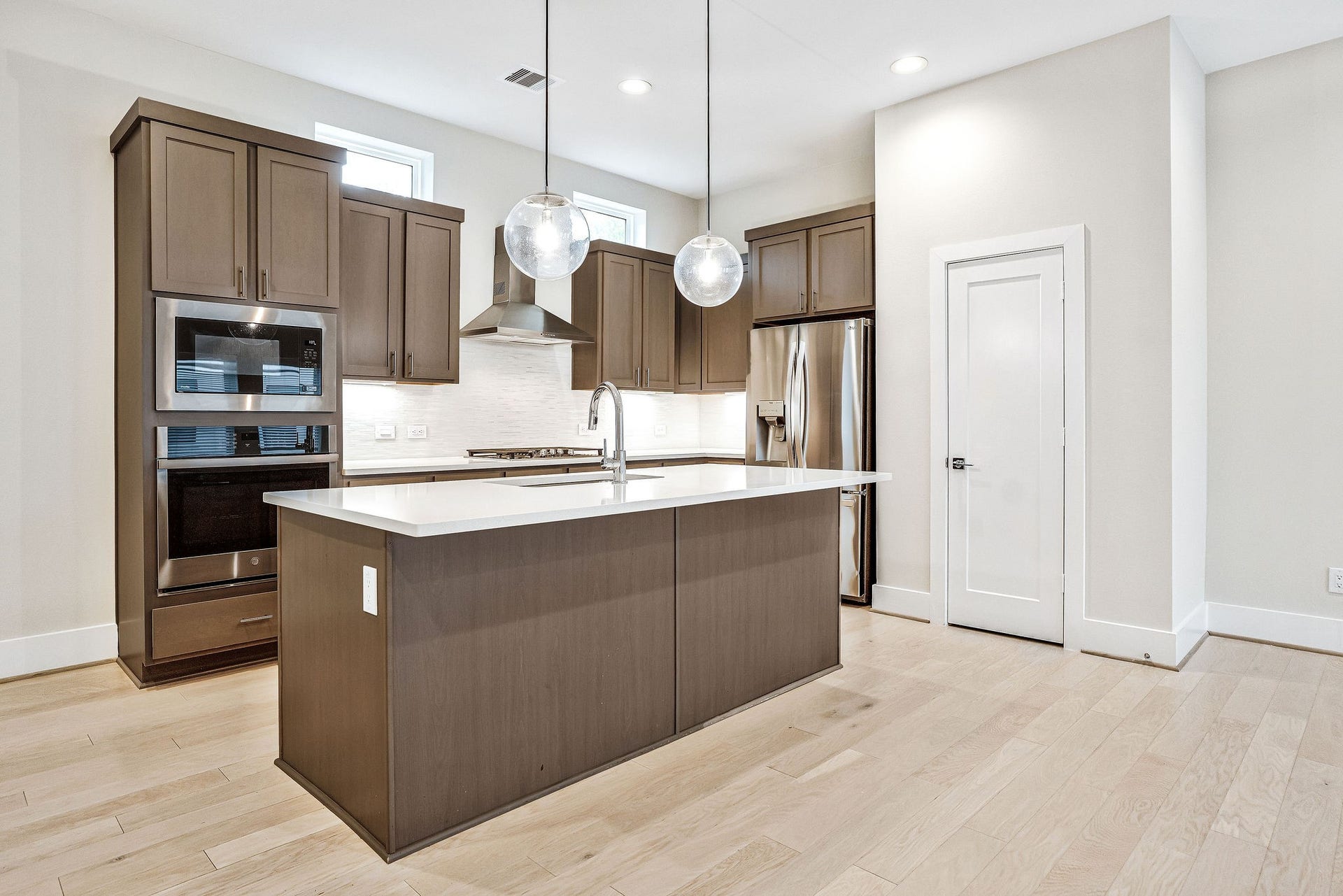838 Fisher Street, #B, Houston, TX 77018 Gorgeous kitchen boasts stainless steel appliances, including a refrigerator, sleek quartz countertops, a designer tile backsplash, and modern globe pendant lighting over the island.
