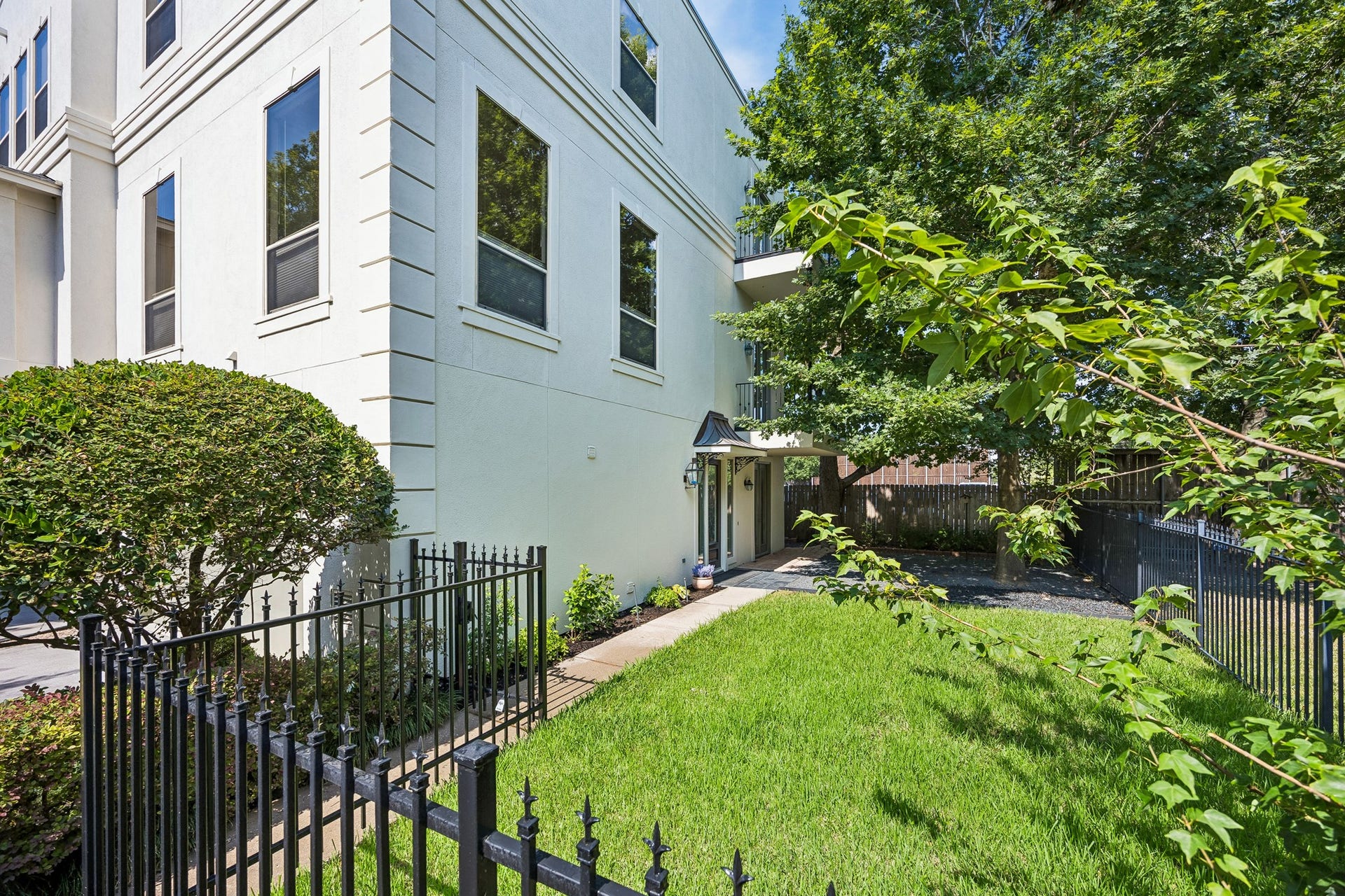 1477 Missouri Street, Houston, TX 77006 Rare private grass yard framed by an iron fence and shaded by established landscaping.