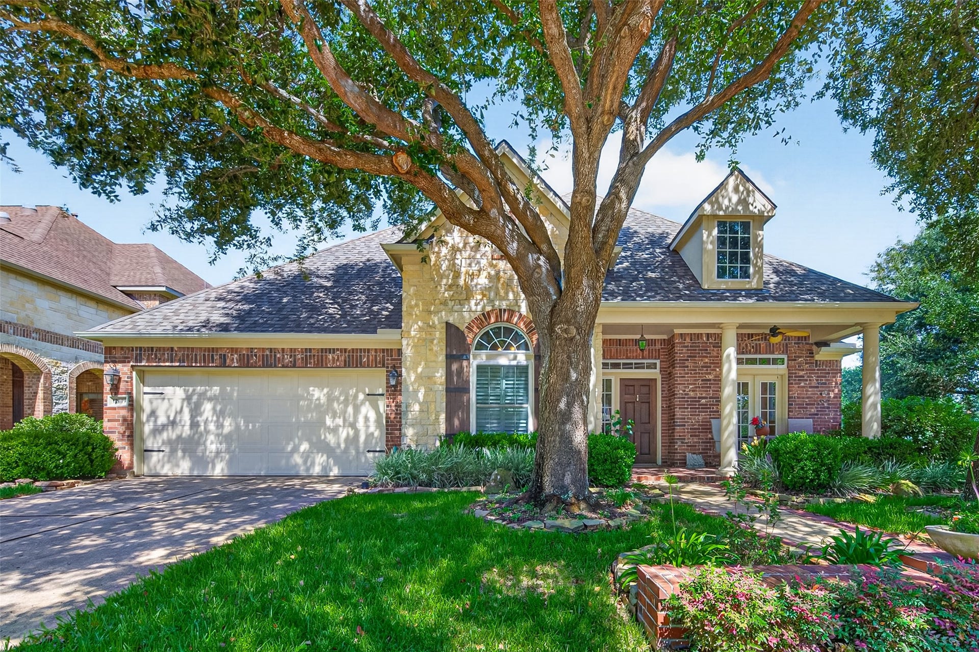 12019 Fullers Grant Court, Cypress, TX 77433 Charming two-story brick home with a welcoming front porch, nestled under a large shade tree with lush landscaping and an attached two-car garage.