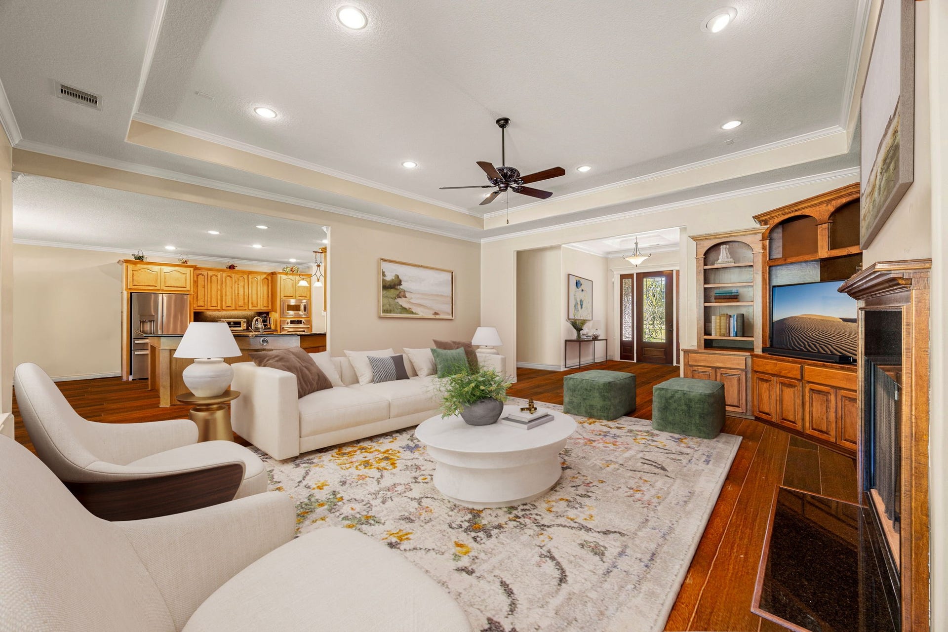 13506 Stagecoach Road, Magnolia, TX 77355 This inviting living room exudes warmth and elegance with its tray ceiling details, hardwood flooring, and beautiful built-in cabinetry framing the fireplace. Expansive windows offer serene views and fill the space with soft natural light, creating the perfect setting for relaxing evenings or lively gatherings.