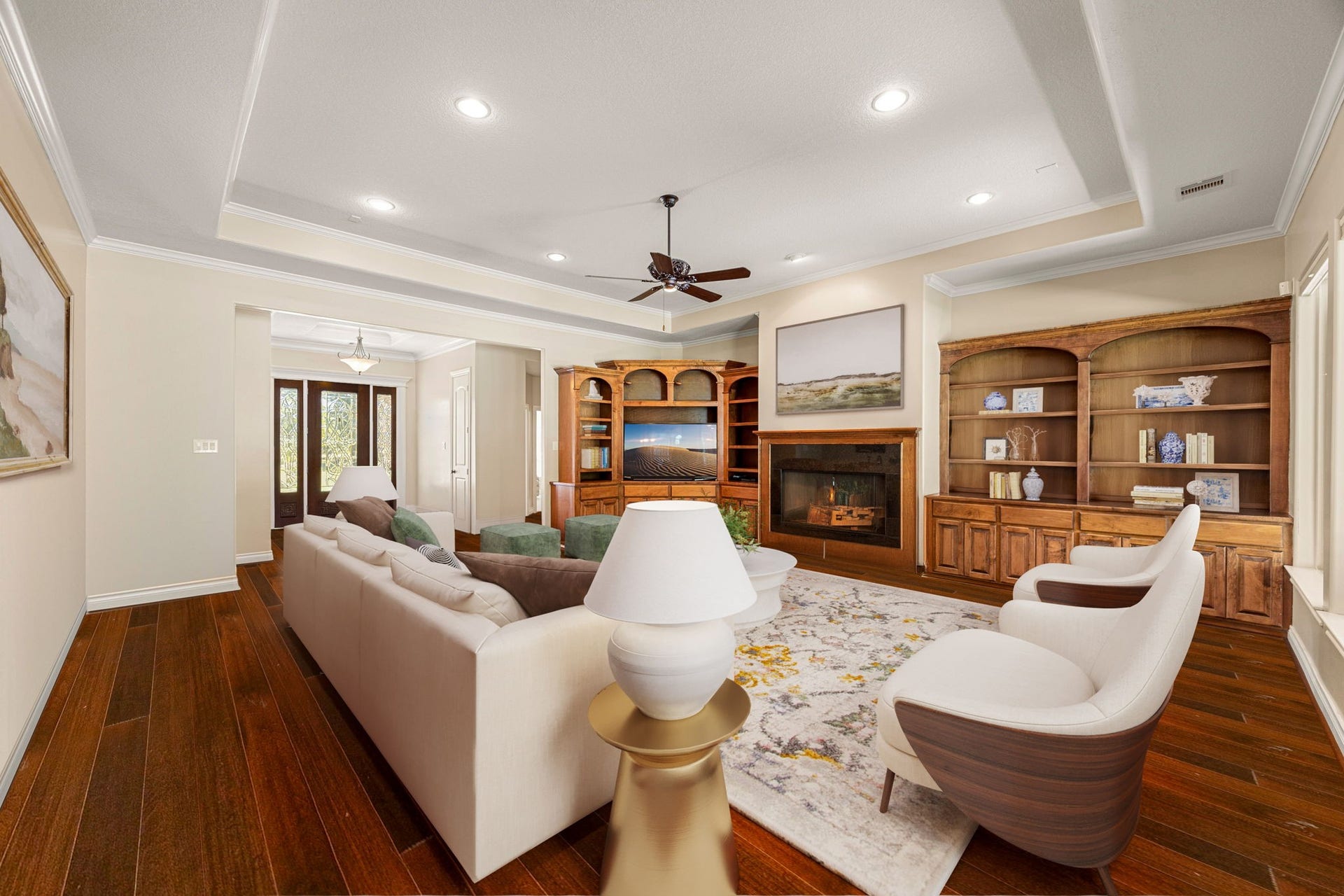13506 Stagecoach Road, Magnolia, TX 77355 This beautiful living area features rich engineered hardwood flooring, elegant tray ceilings, and a warm fireplace framed by custom built-ins. Large windows fill the space with natural light, creating a bright and inviting ambiance. Perfectly positioned near the entryway, this room offers both comfort and sophistication for relaxing or entertaining.