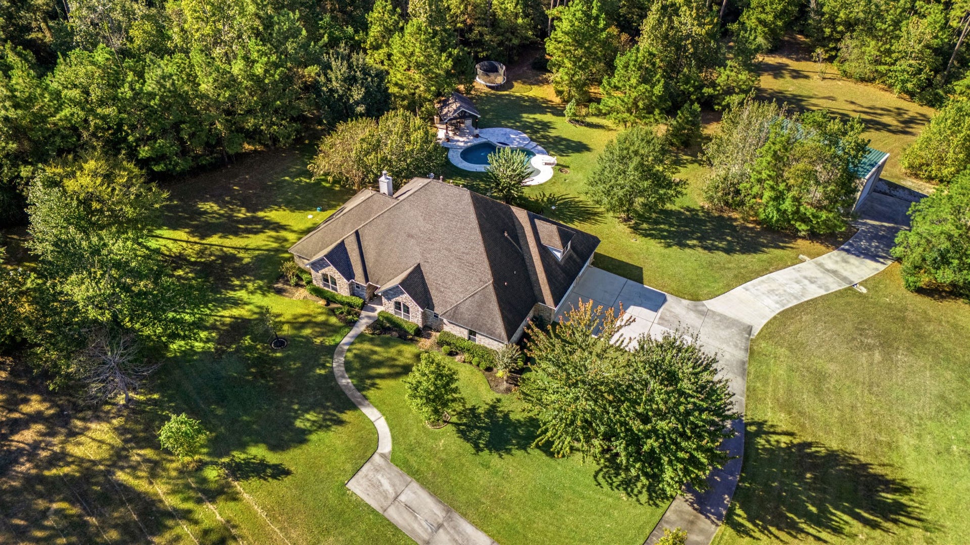 13506 Stagecoach Road, Magnolia, TX 77355 Welcome home to 13506 Stagecoach Road, a stunning country estate nestled on over 12+ wooded acres in Eagle Point, zoned to Tomball ISD. This private retreat offers timeless charm with a classic brick elevation, lush rolling lawn, and an expansive workshop. Enjoy peaceful views of your private pond or entertain outdoors in the custom oasis featuring a heated pool and fully equipped outdoor kitchen, the perfect blend of luxury and country living just minutes from city conveniences.