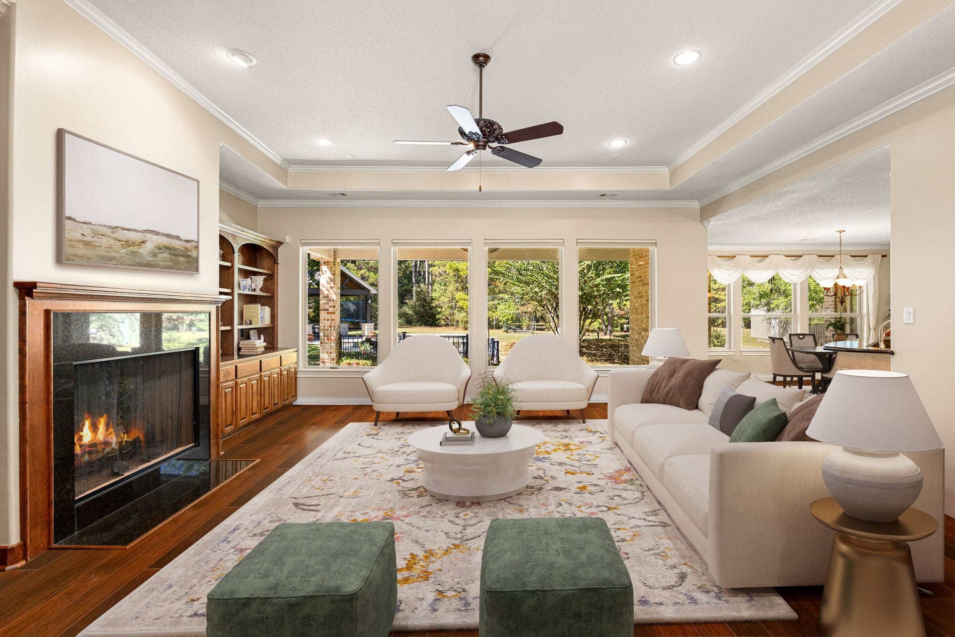 13506 Stagecoach Road, Magnolia, TX 77355 This elegant living room offers a warm and inviting atmosphere with rich hardwood flooring, a cozy fireplace, and custom built-in cabinetry. Large picture windows frame peaceful views of the outdoors, filling the space with natural light. The open layout seamlessly connects to the dining area, creating an ideal setting for both entertaining and everyday living.