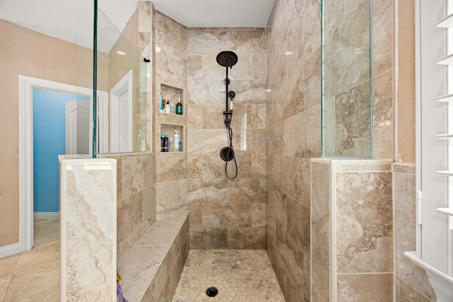 13506 Stagecoach Road, Magnolia, TX 77355 The walk-in shower offers a true spa-like experience with elegant tile from floor to ceiling, a built-in bench, recessed shelving, and a rainfall showerhead, creating the perfect space to unwind in comfort and style.