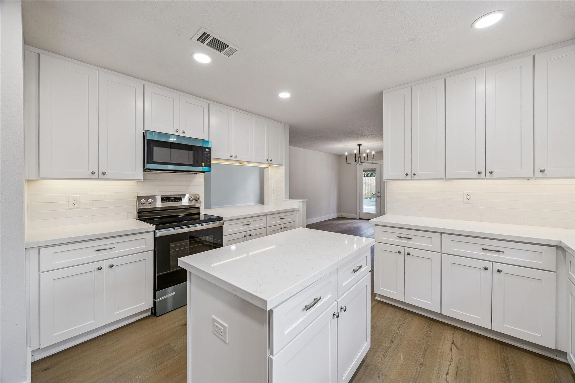 11947 Fawnview Drive, Houston, TX 77070 Kitchen continuation showcasing Carrara quartz island and perimeter countertops, new cabinetry with updated hardware, new stainless appliances, and white oak LVP flooring. Every detail is new.