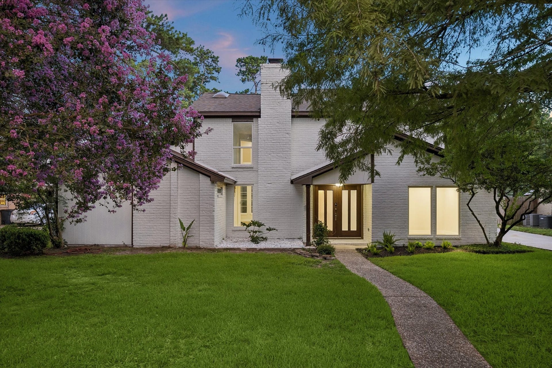 11947 Fawnview Drive, Houston, TX 77070 Freshly painted original brick elevation showcasing a fully renovated home with new 30-year architectural shingle roof, new windows, and new exterior doors. Lush manicured lawn with mature trees and updated curb appeal.