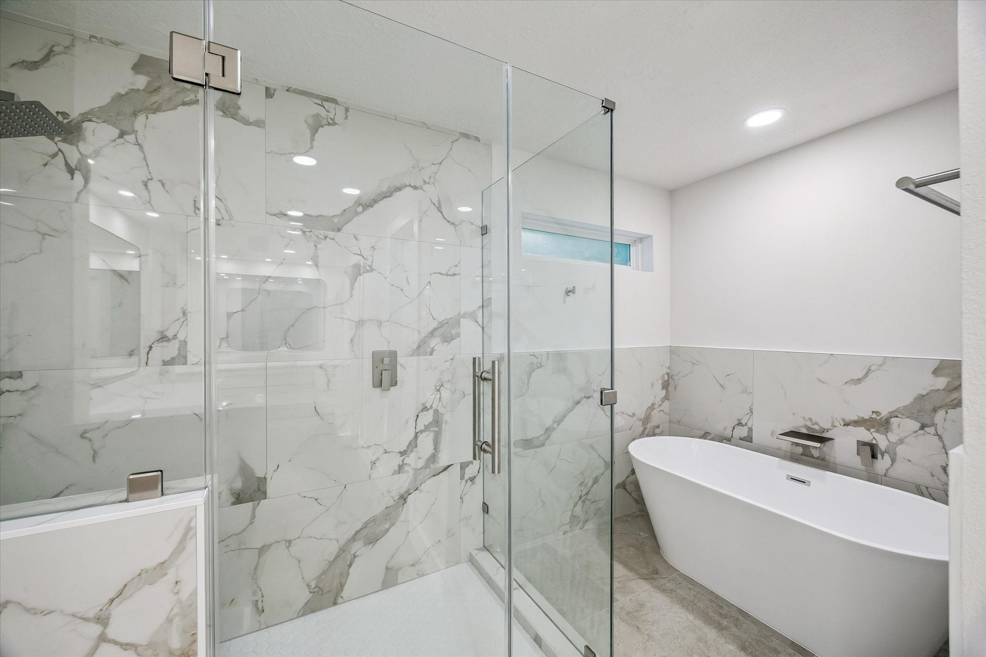 11947 Fawnview Drive, Houston, TX 77070 Master bathroom reimagined with large-porcelain tile, frameless shower enclosure, large soaking tub, w. waterfall faucet head, chrome finishes.