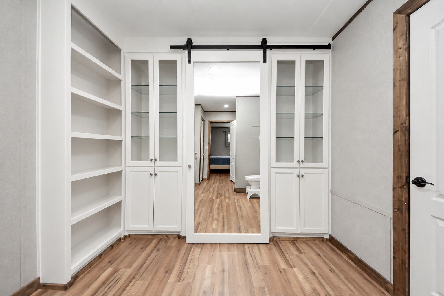 12565 Royal Green Drive, Conroe, TX 77303 Bathroom built-in shelving and glass-front storage cabinets with sliding mirrored barn door.