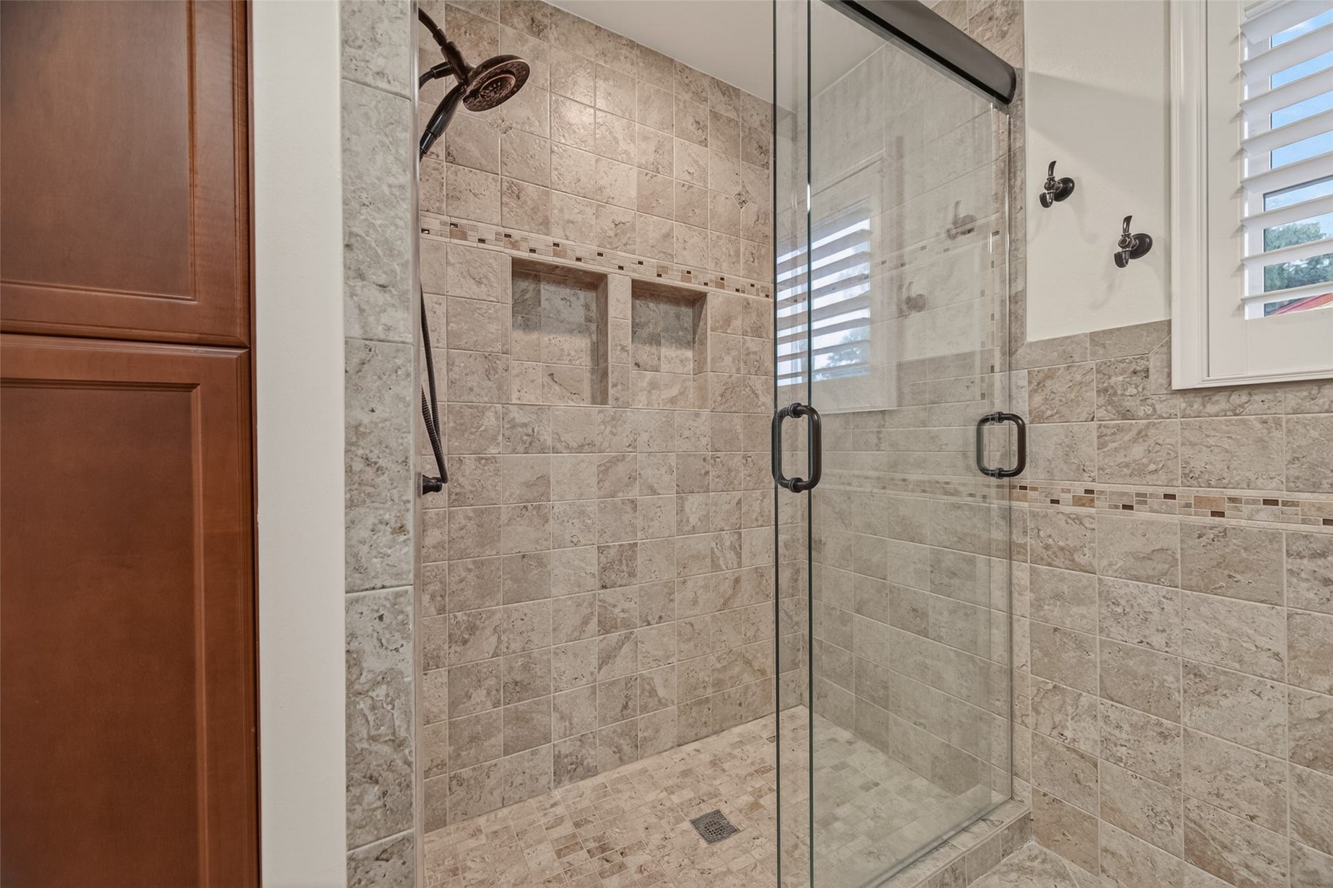5638 Sanford Road, Houston, TX 77096 Remodel featuring a low-threshold, oversized walk-in glass shower, elegant tilework, built-in shower shelving, and accessible, functional design.