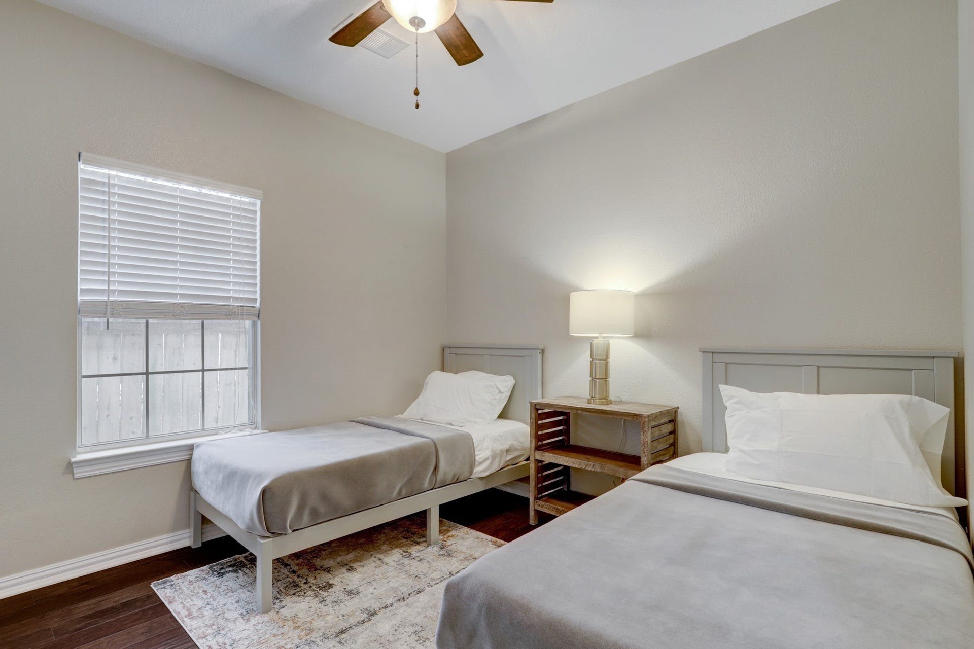 803 Dorothy Street, Houston, TX 77007 Comfortable furnished bedroom with two beds, beautiful wood flooring, a ceiling fan, and plenty of natural light.