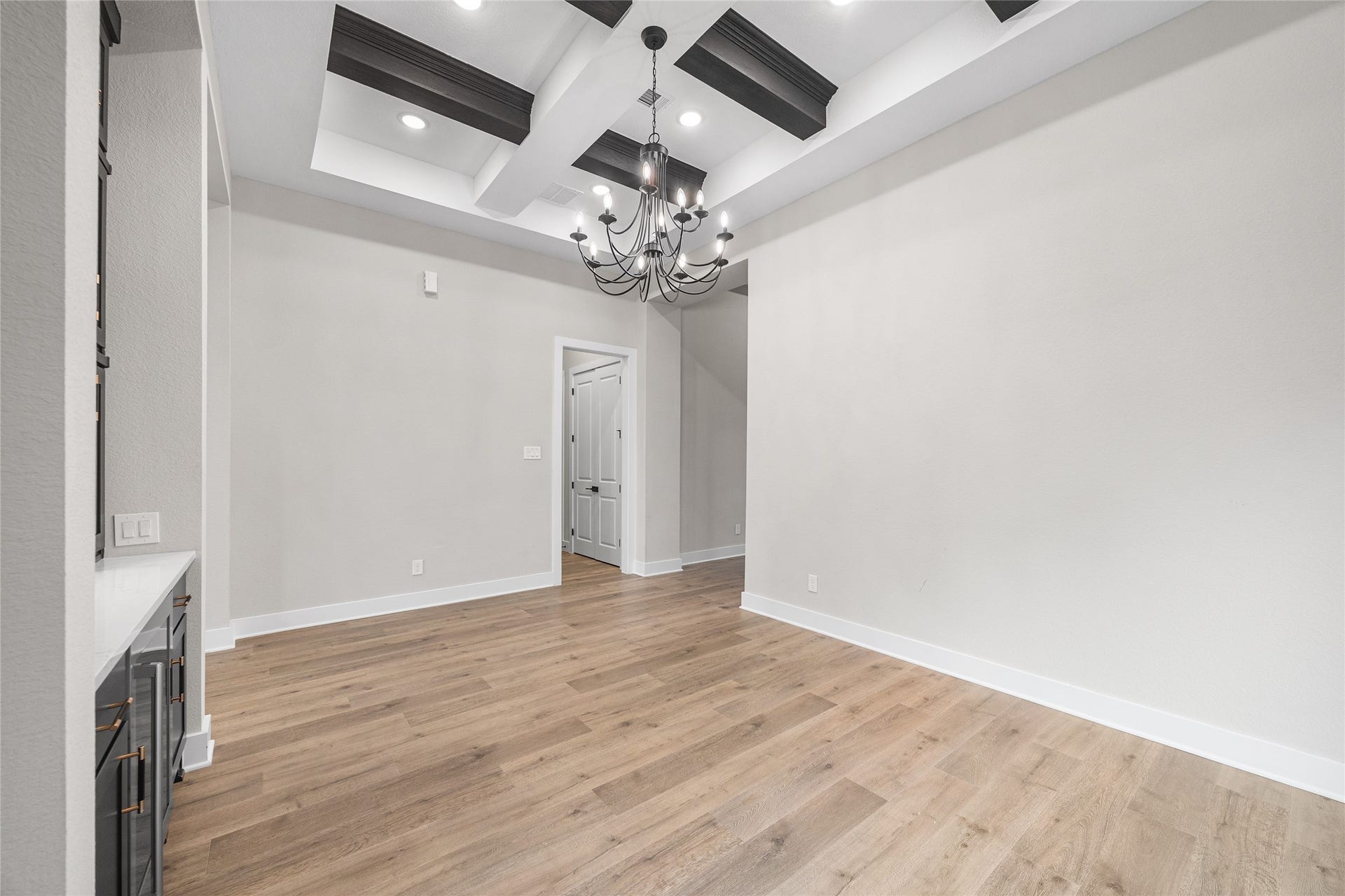 6707 Nimitz Court, Katy, TX 77493 Elegant dining space featuring a tray ceiling with exposed beams and a statement chandelier, offering a refined setting for gatherings and everyday meals.